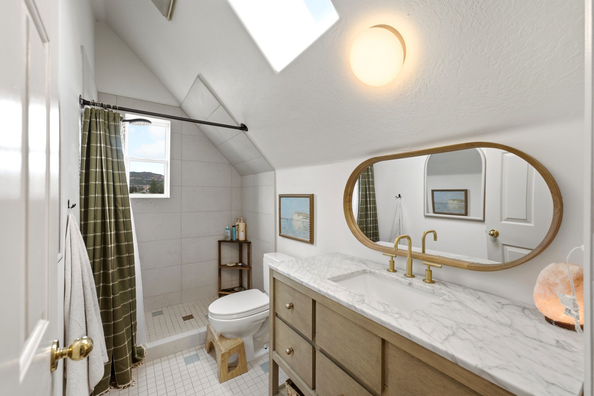 Bathroom featuring a single vanity with stone countertop, brass-finish fixtures, and a wood-frame oval mirror