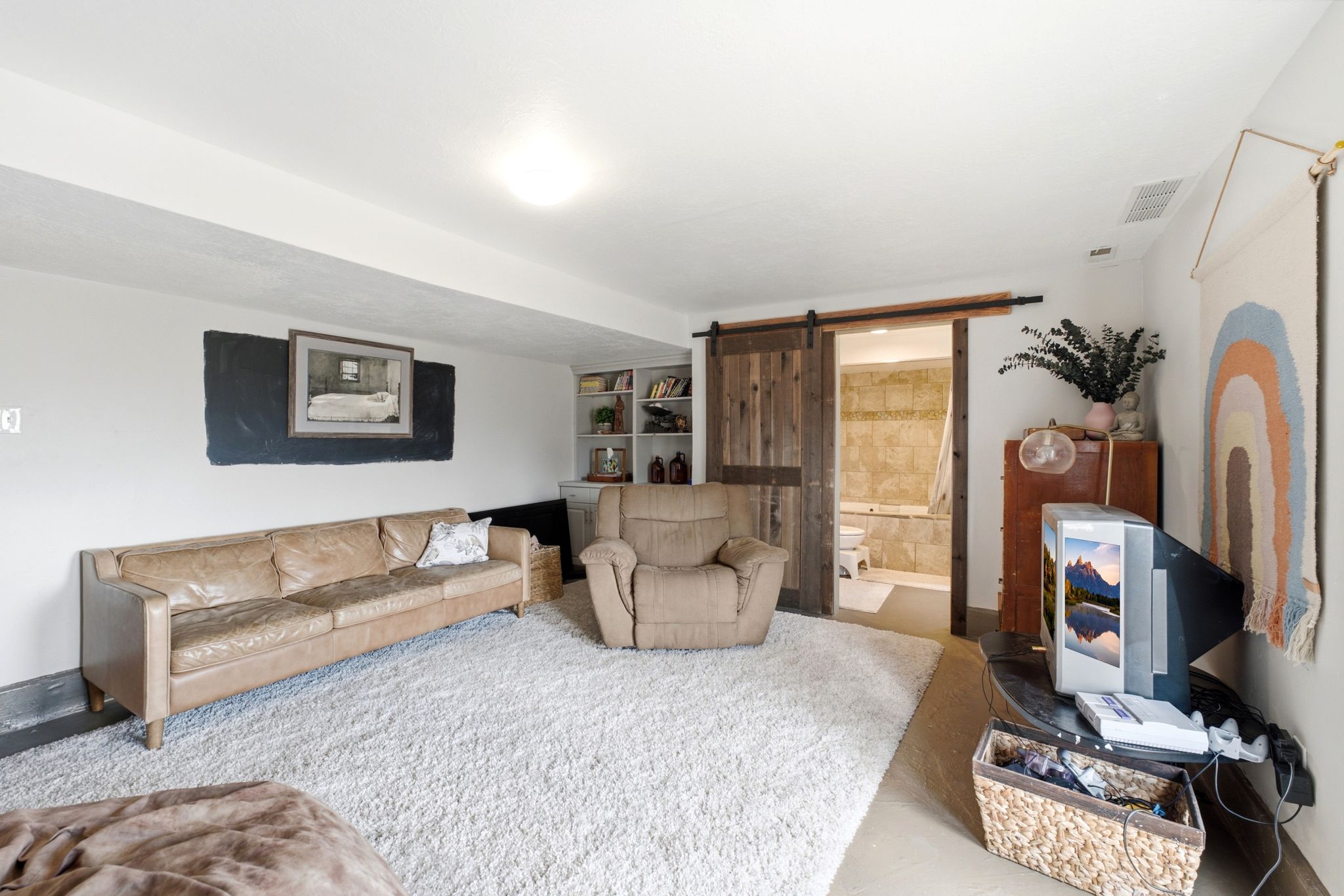 Living area featuring a textured white ceiling, light-colored walls, and a large plush area rug