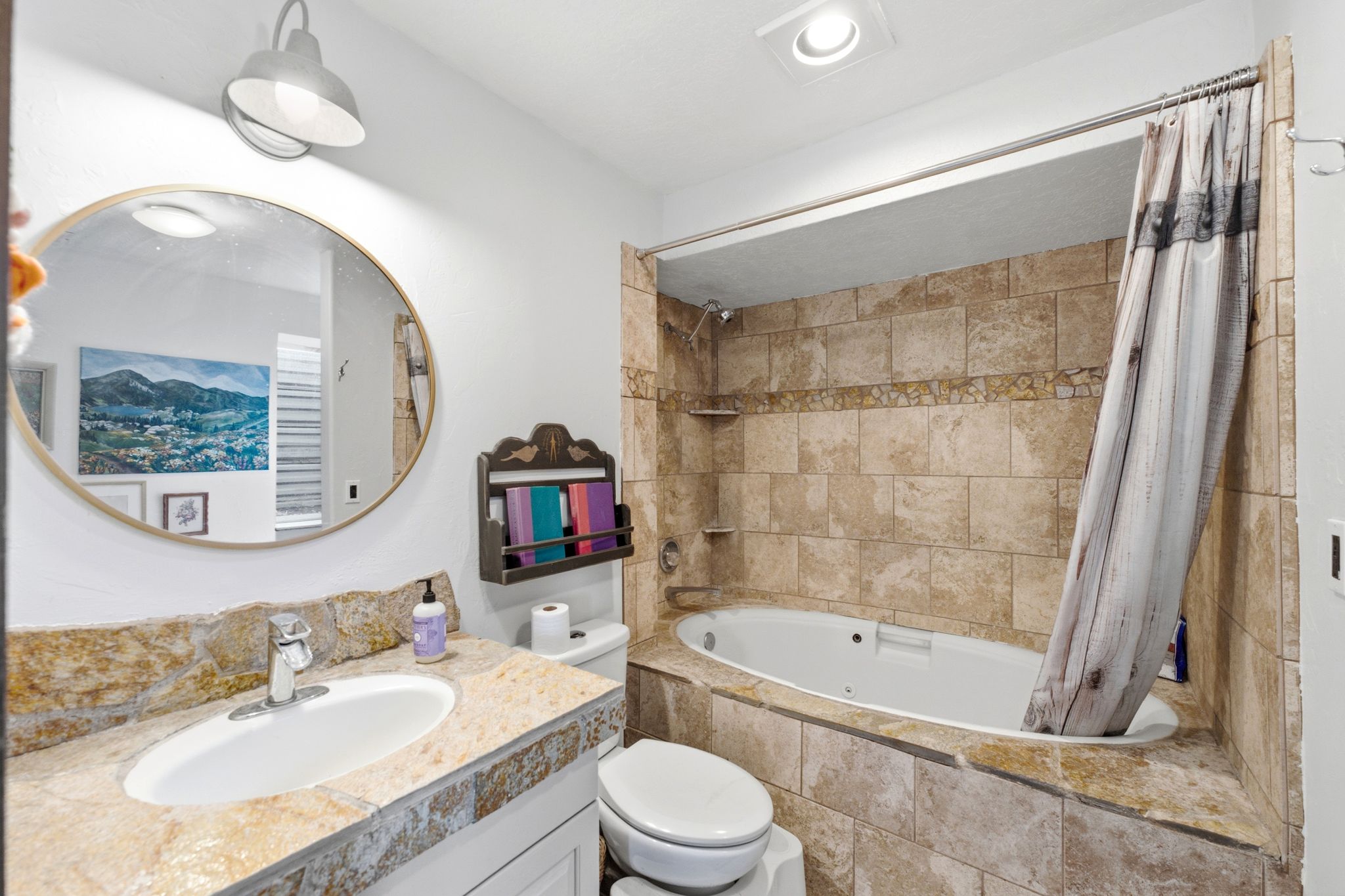 Bathroom featuring a jetted tub surrounded by natural stone-look tiling