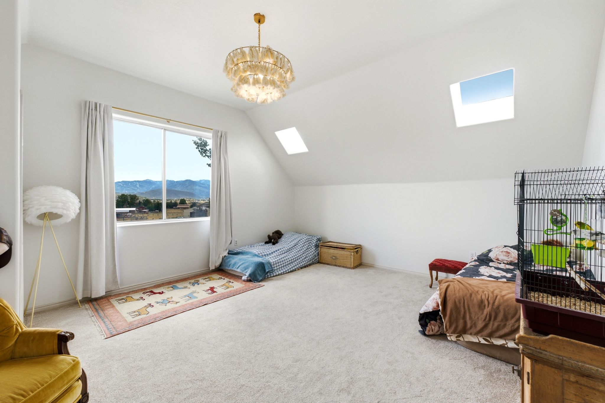 Spacious room featuring a prominent window, two skylights, a contemporary chandelier, and light-toned carpeting