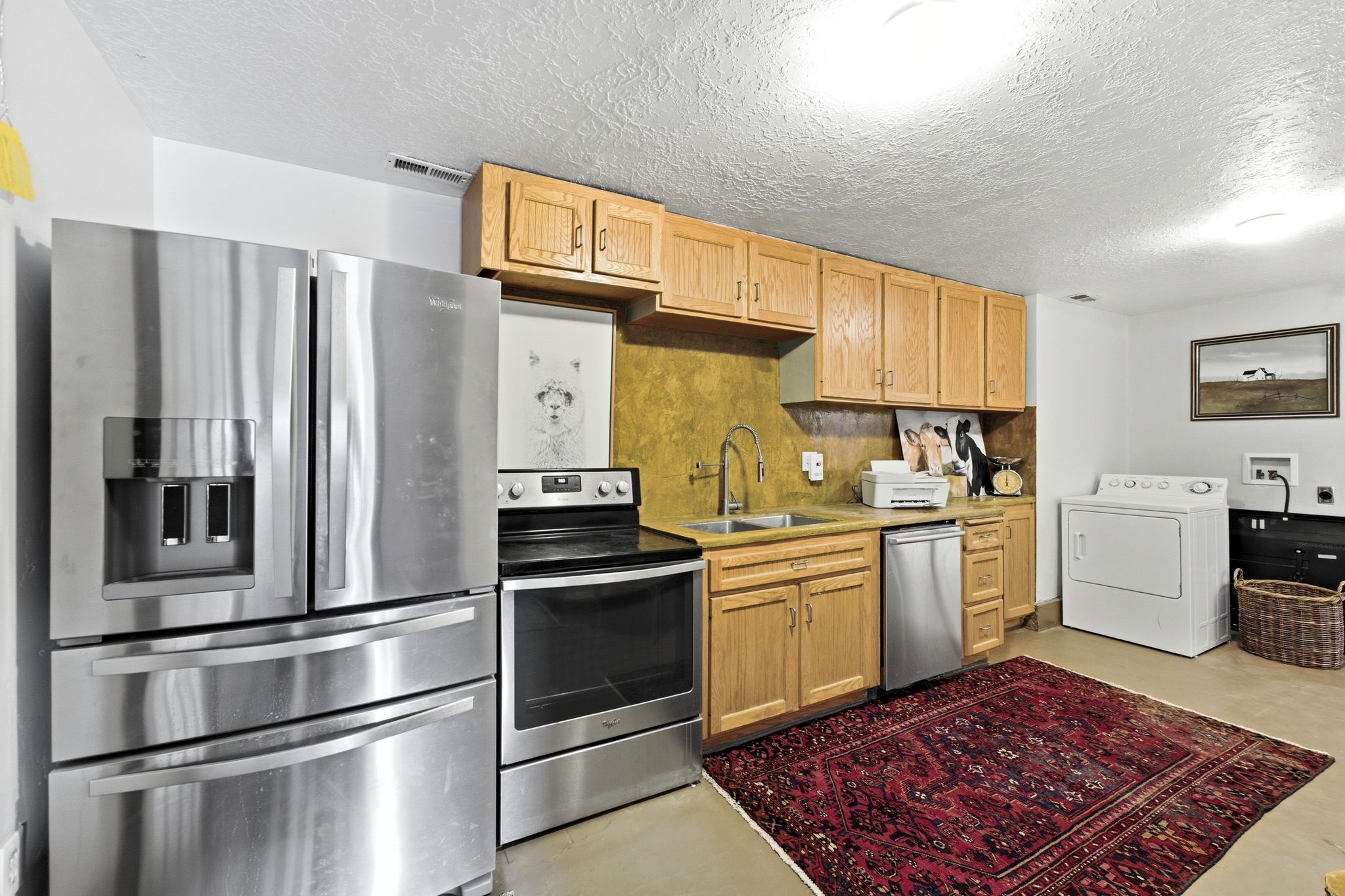 Utility room with a stainless steel French door refrigerator, stainless steel electric range, wood cabinetry, and a washer and dryer set