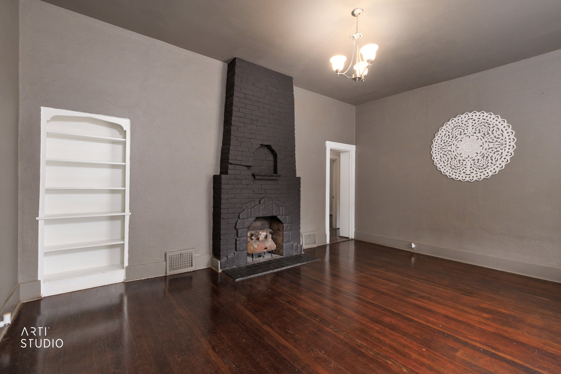 Spacious room featuring dark wood-finish flooring and a painted brick fireplace