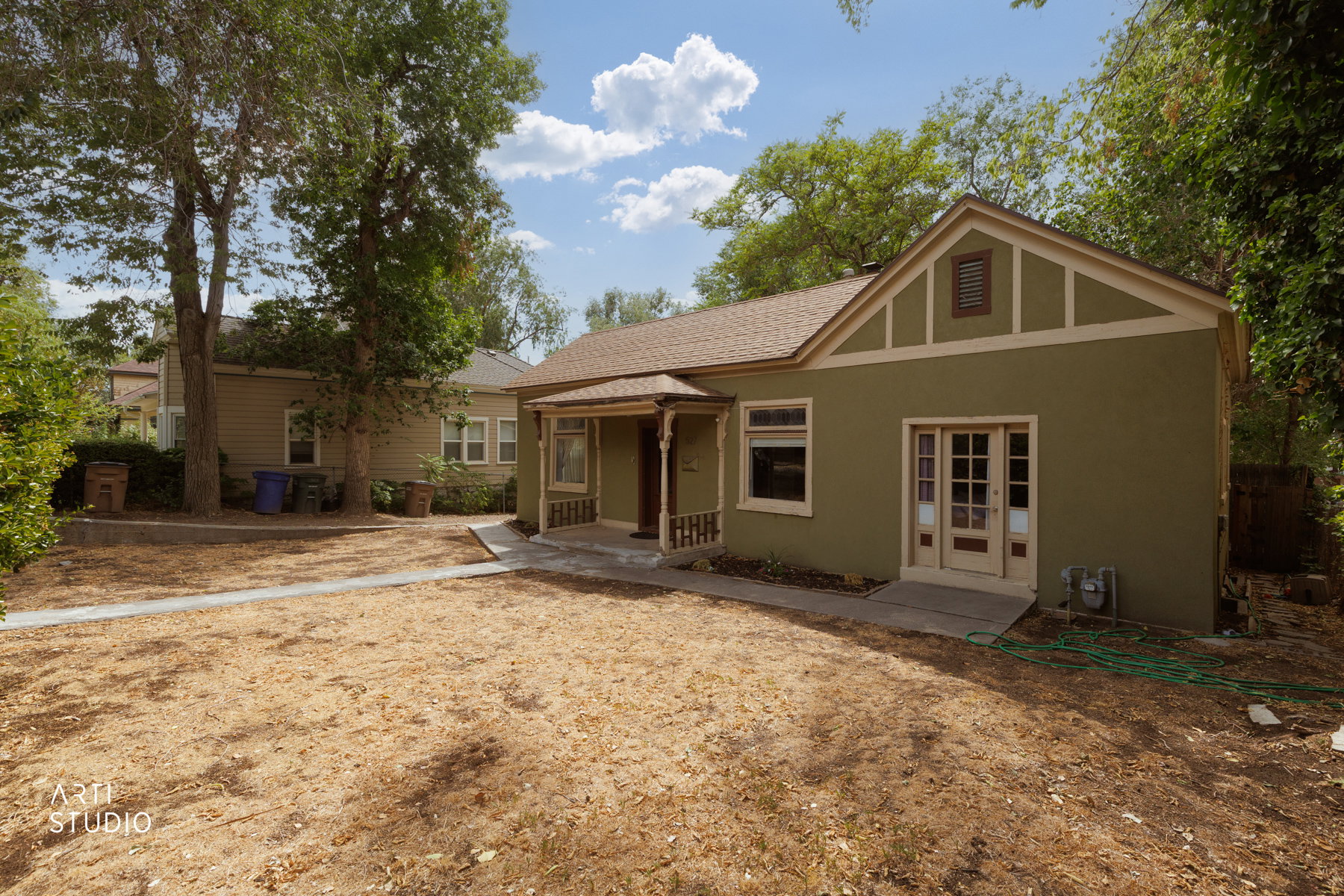 Single-story residence featuring a green stucco exterior with cream trim accents and a gable roofline