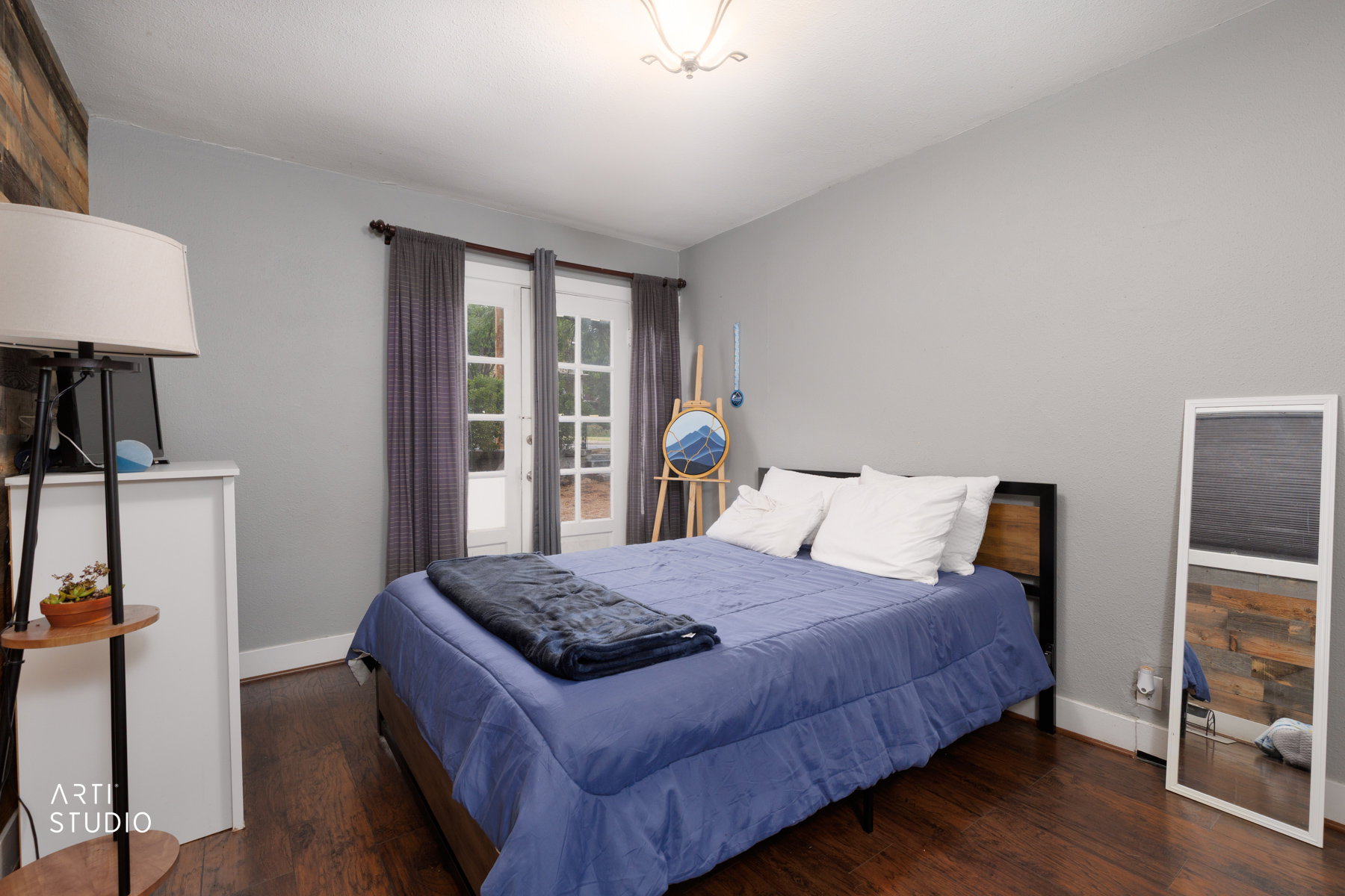 Bedroom featuring wood-finish flooring, light grey walls, and a wood-paneled accent wall