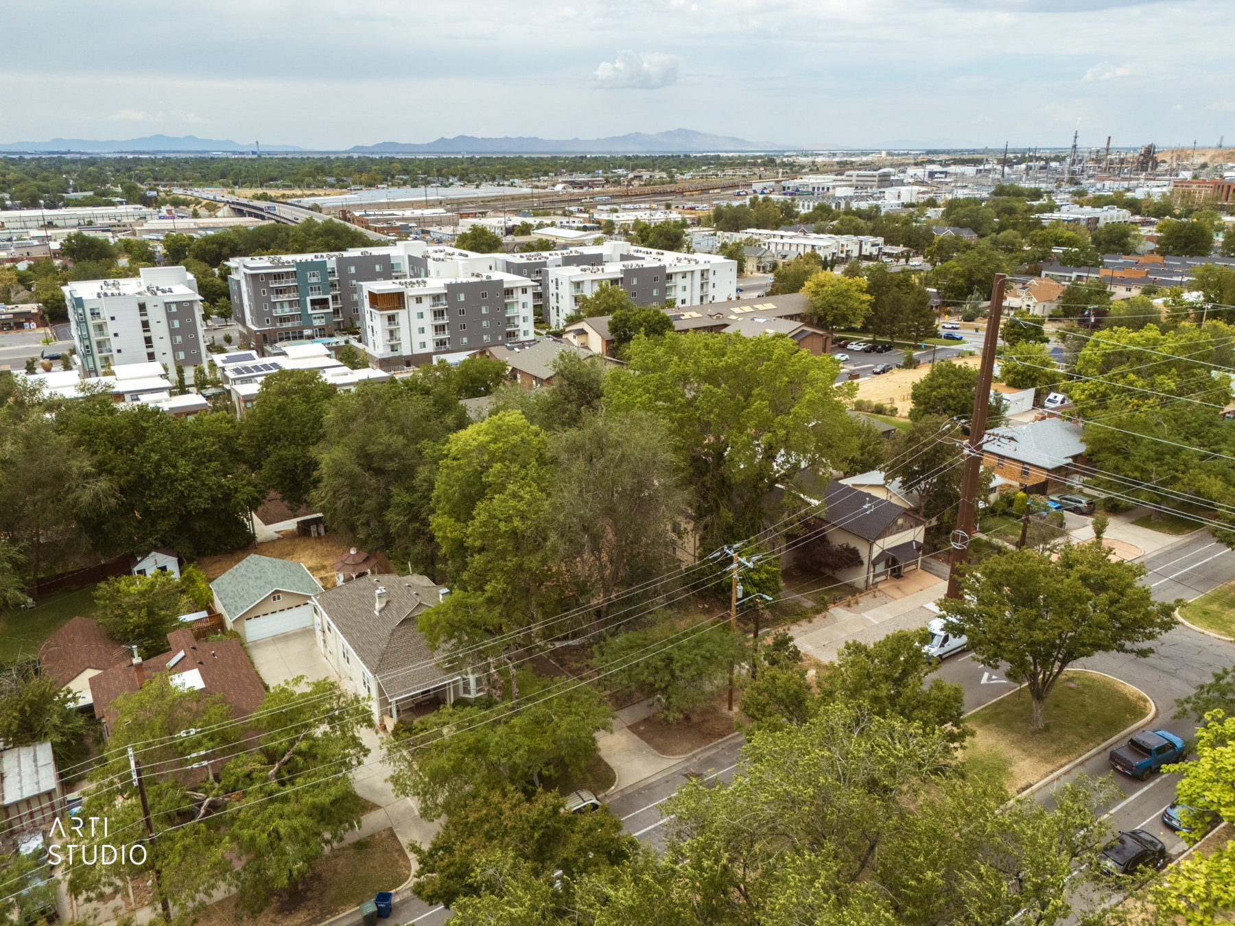 Aerial perspective showcasing residential properties amidst mature trees and paved roads, with contemporary multi-story buildings in the background