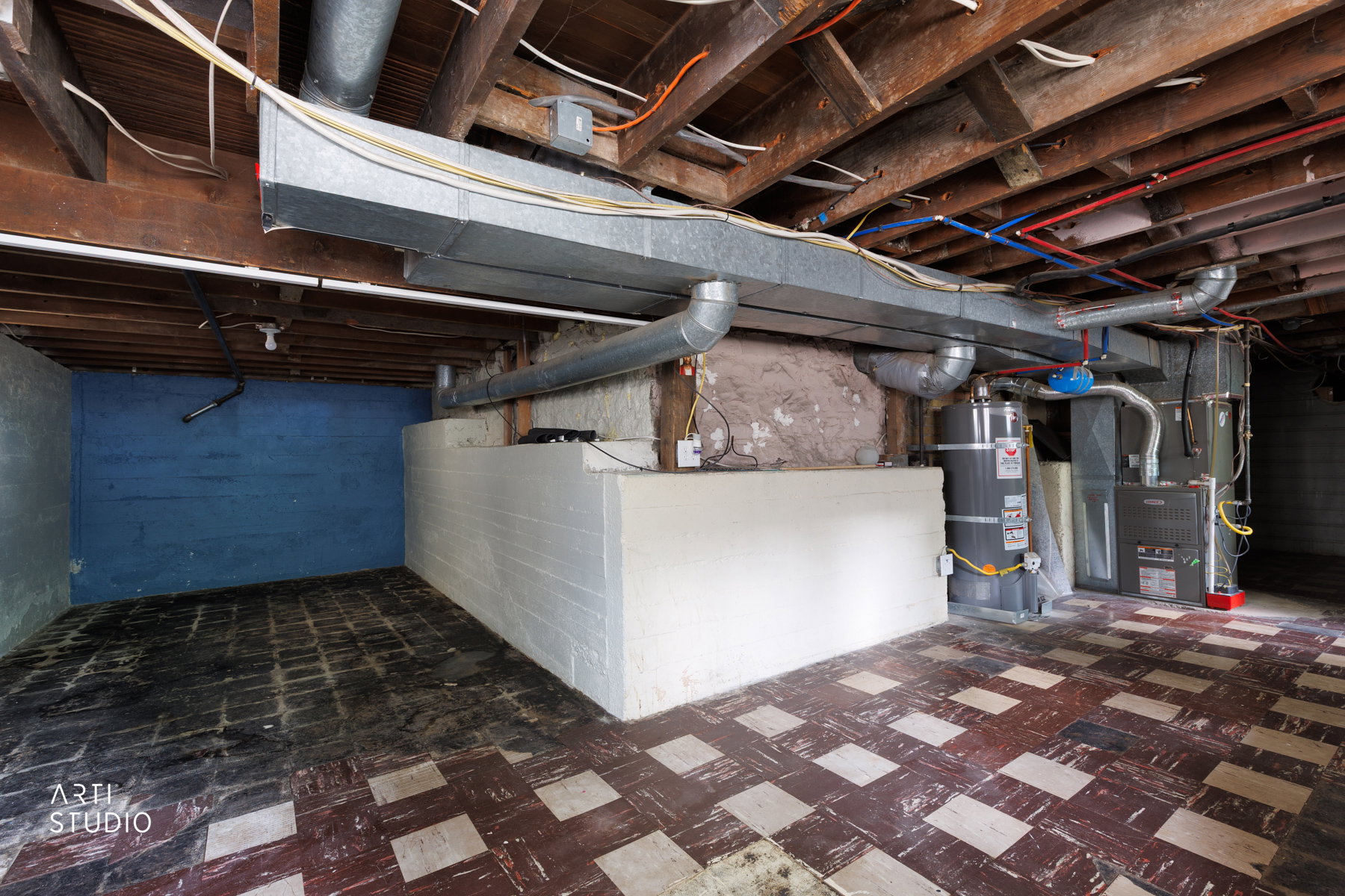 Basement utility area featuring exposed wood ceiling joists, ductwork, and various piping