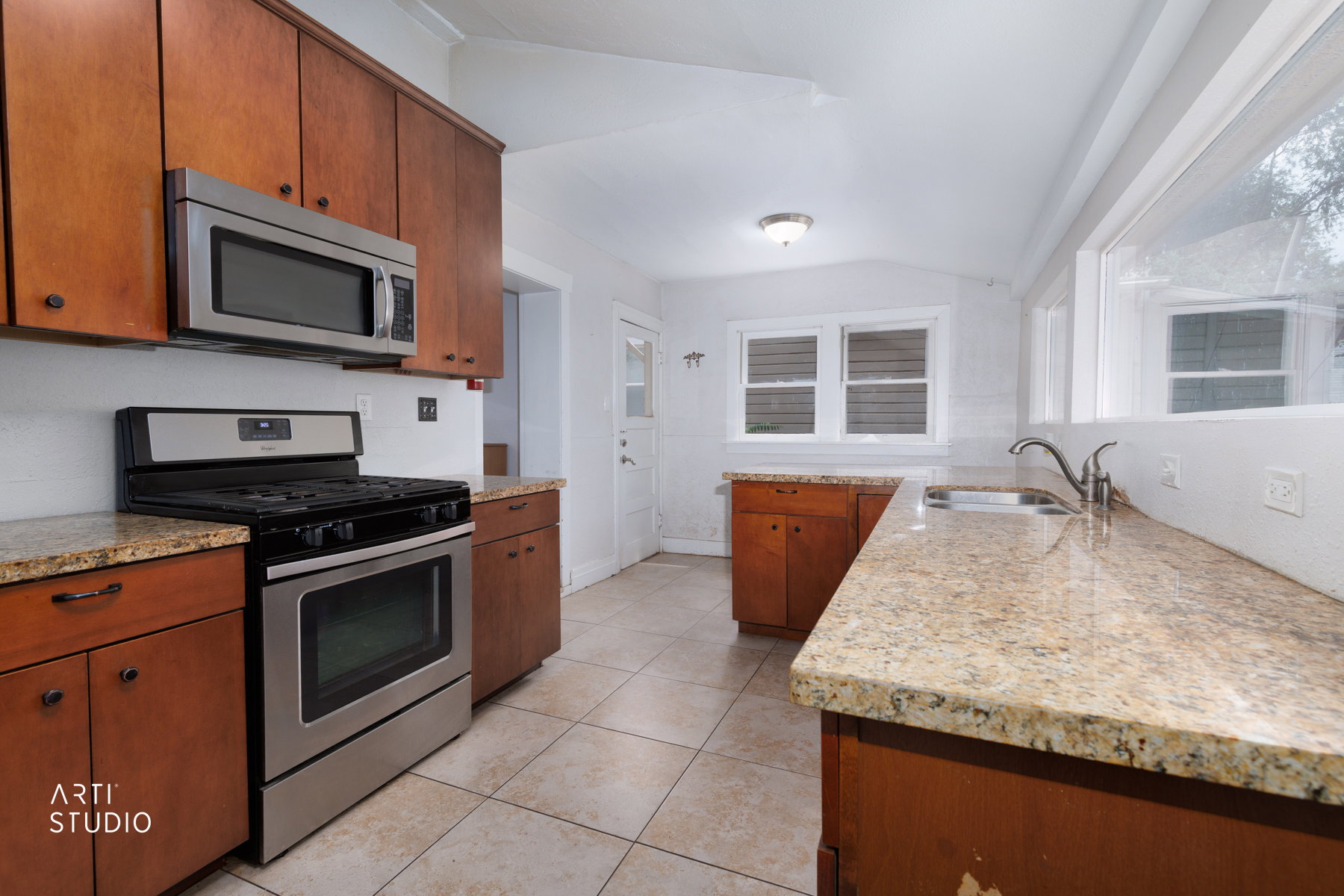 Kitchen featuring wood cabinetry, light-toned countertops, tile flooring, stainless steel range, and an over-the-range microwave