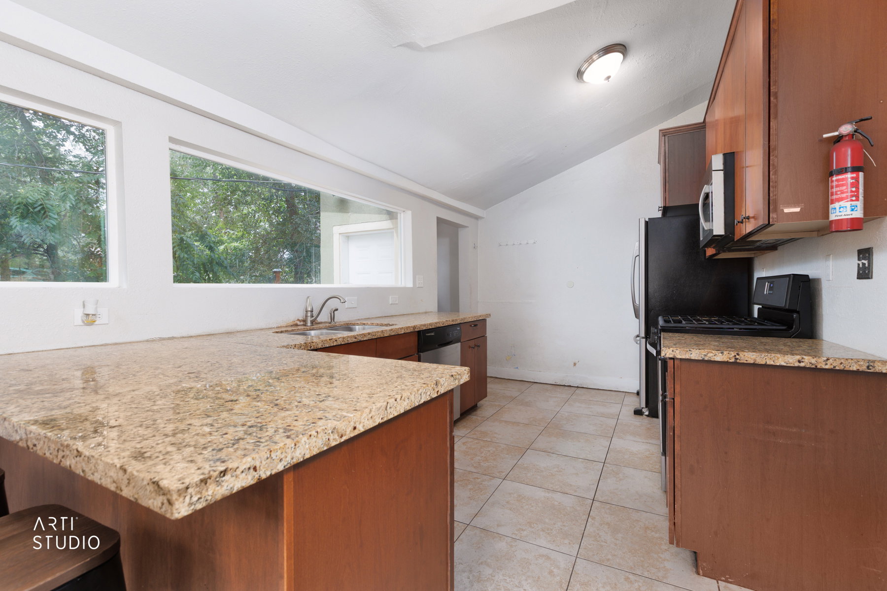 Kitchen featuring a U-shaped countertop with a breakfast bar extension, a stainless steel double-basin sink, and a four-burner gas range