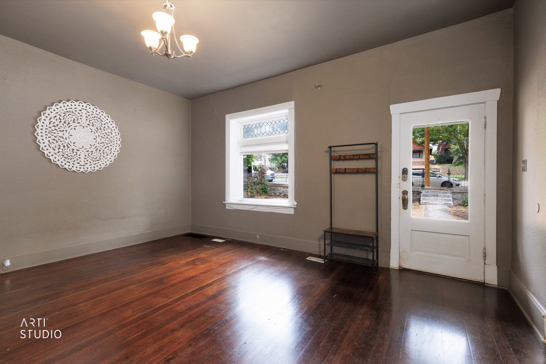 Entryway featuring rich wood-finish flooring, a white paneled door with clear glass, and a large window with decorative upper glasswork