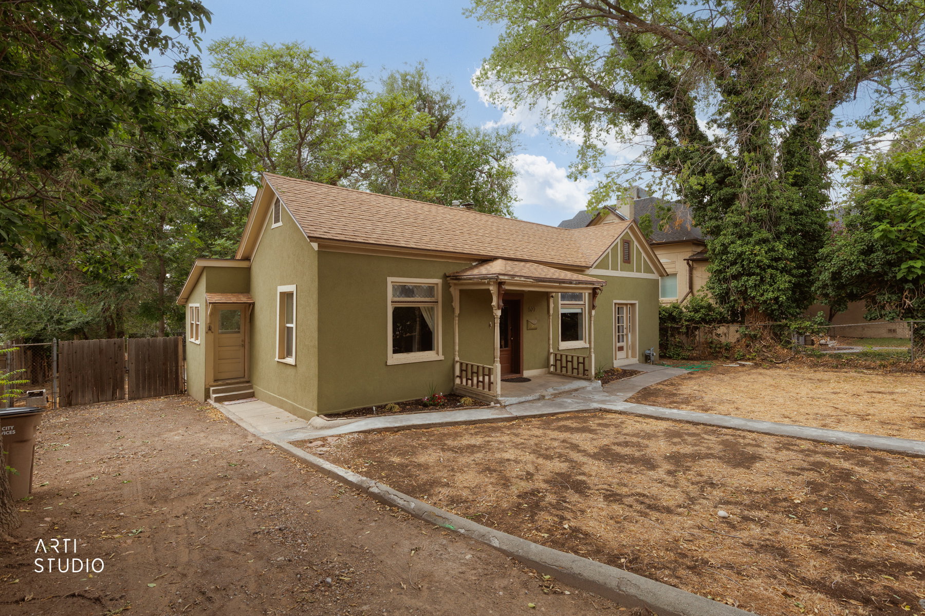 Stucco exterior with a peaked roofline, featuring a covered front porch with wood railings and a front-facing gable