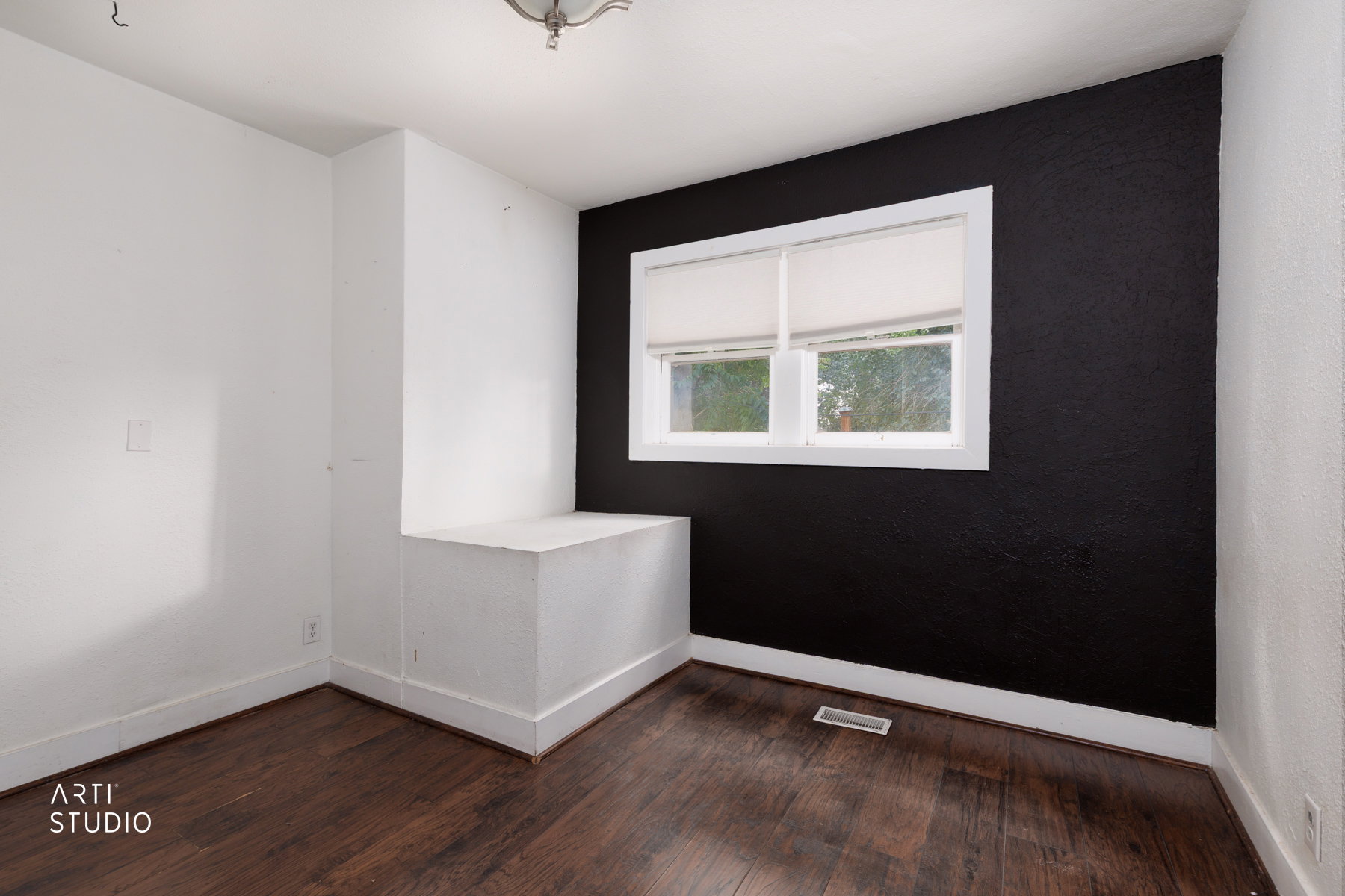 Interior room featuring wood-finish flooring, a window with white trim, and a built-in window seat