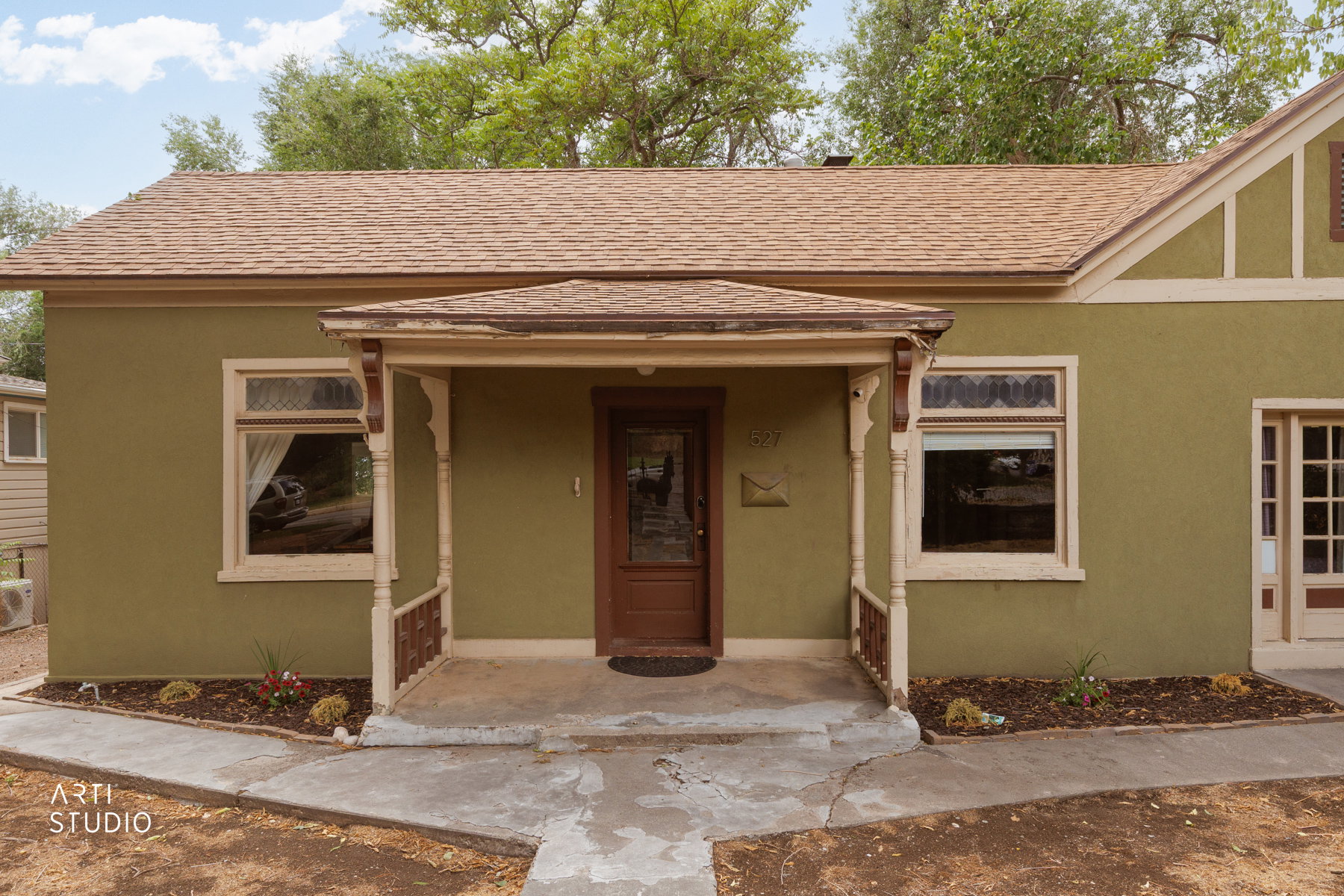 Olive green stucco exterior with a covered entry porch