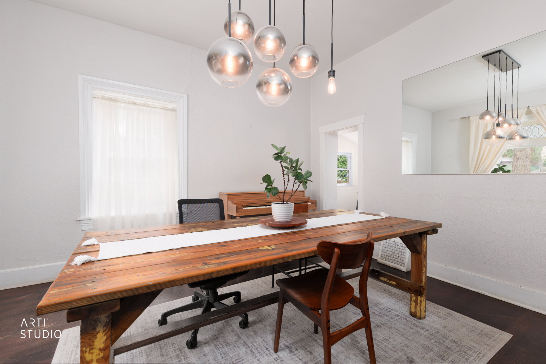 Spacious room featuring a multi-light pendant fixture, dark wood-finish flooring, and a large wall-mounted mirror