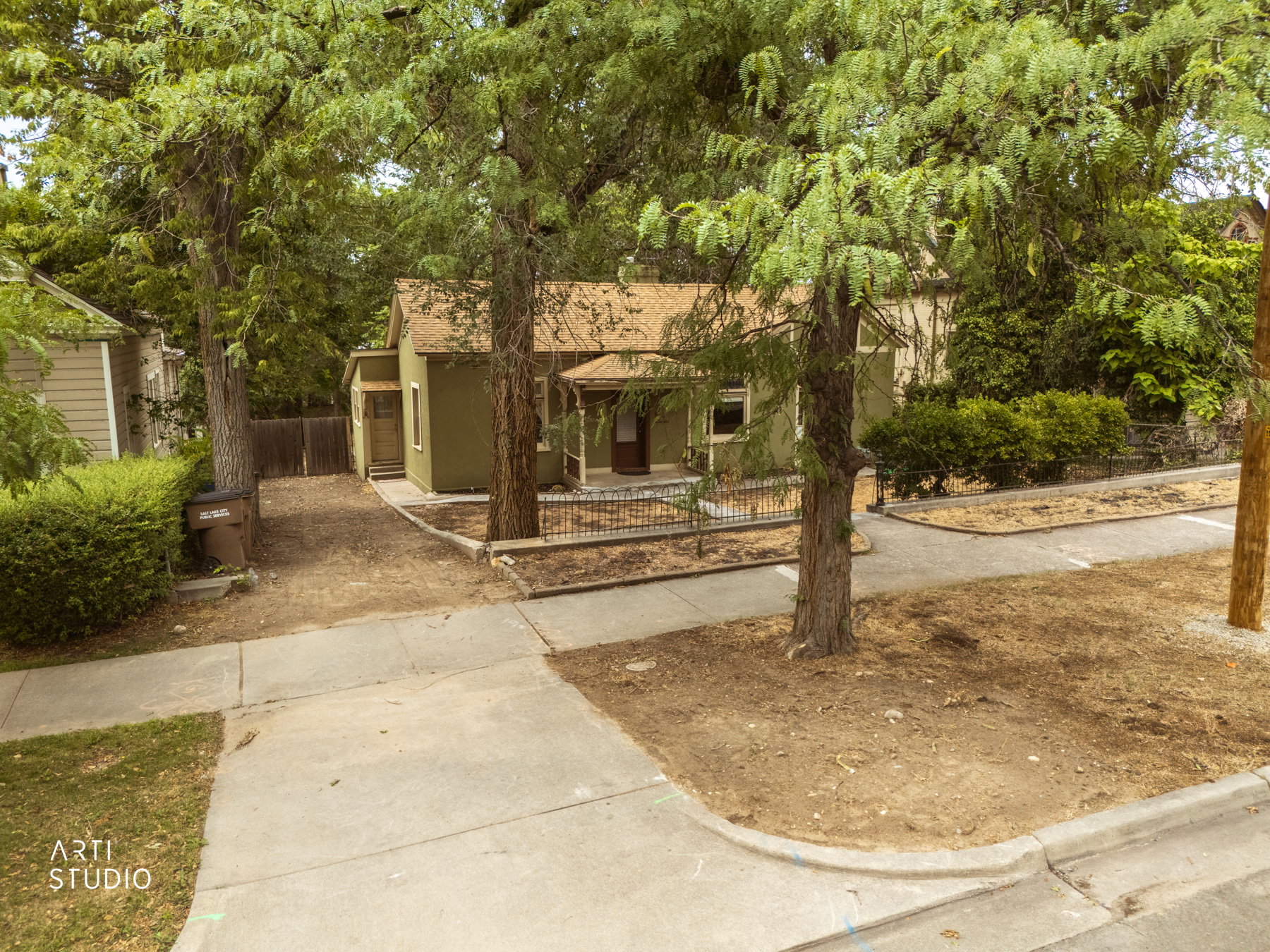 Single-story residence featuring an olive green exterior and a covered front porch with a black wrought iron fence