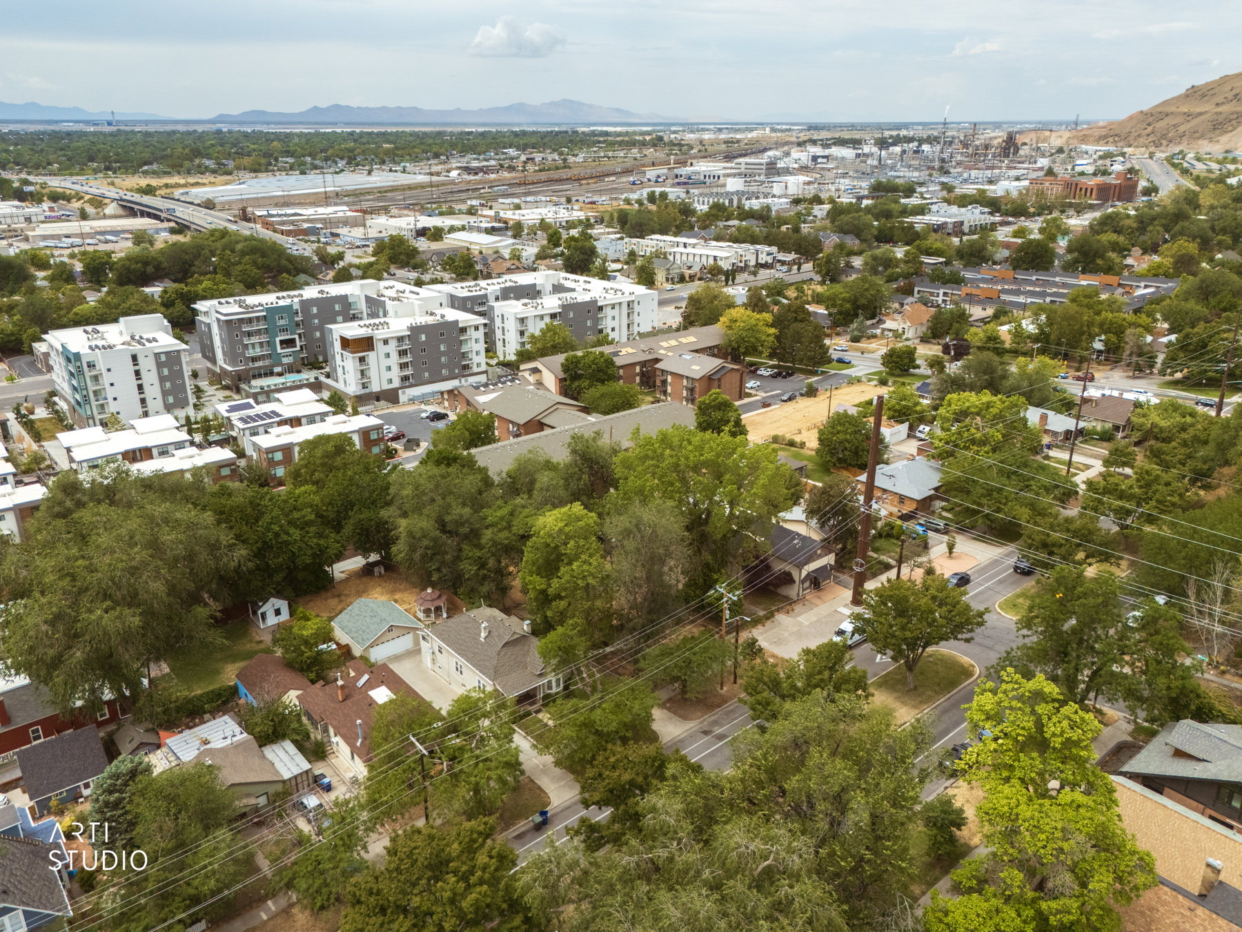 Aerial overview showcasing a mixed-use neighborhood with residential buildings, mature trees, and a mountain backdrop