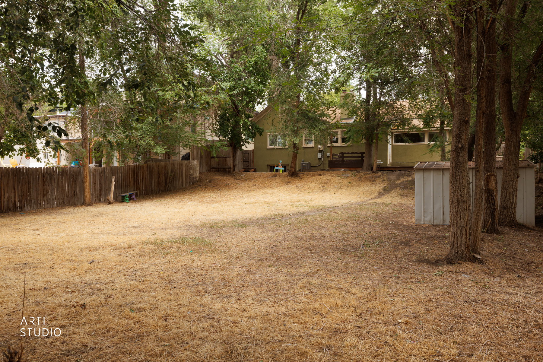 Expansive backyard with a sloped landscape and mature trees