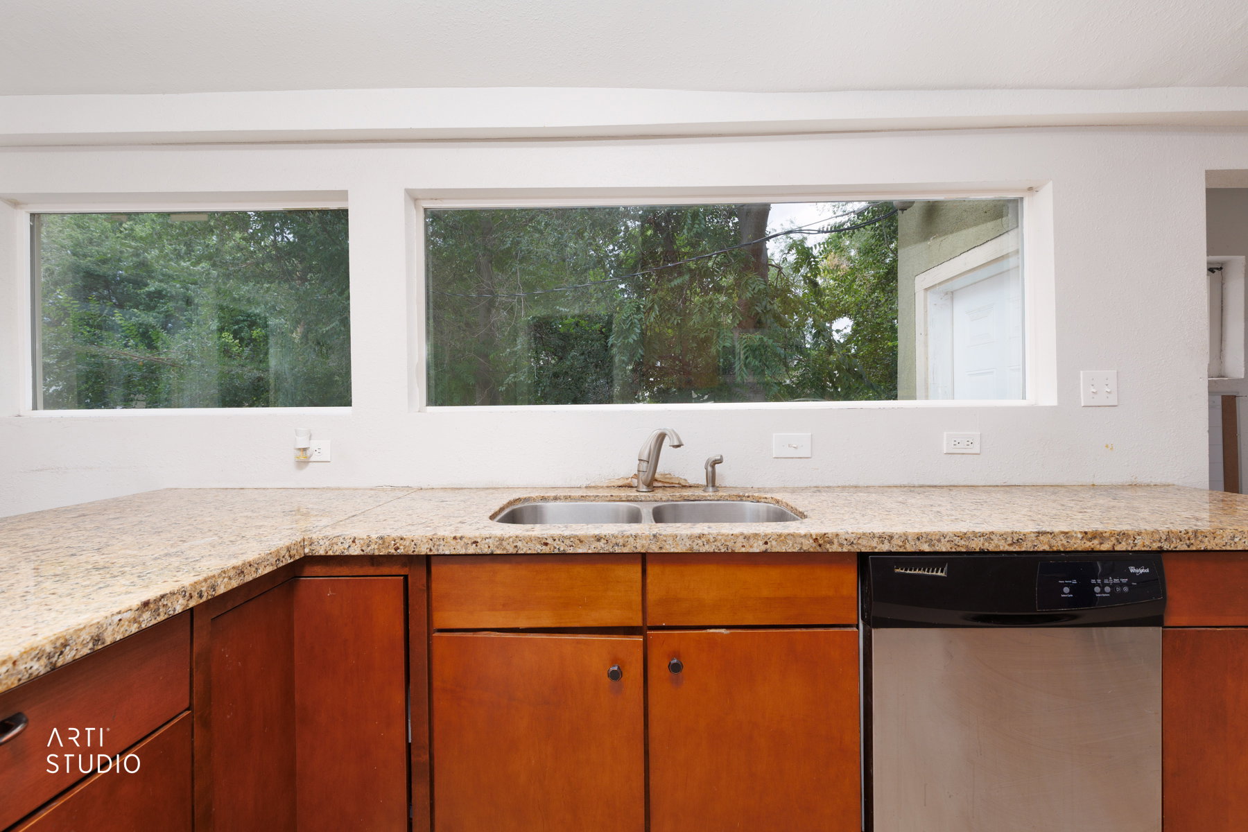 Kitchen featuring light-toned granite countertops, a stainless steel double basin sink, and wood-finish cabinetry