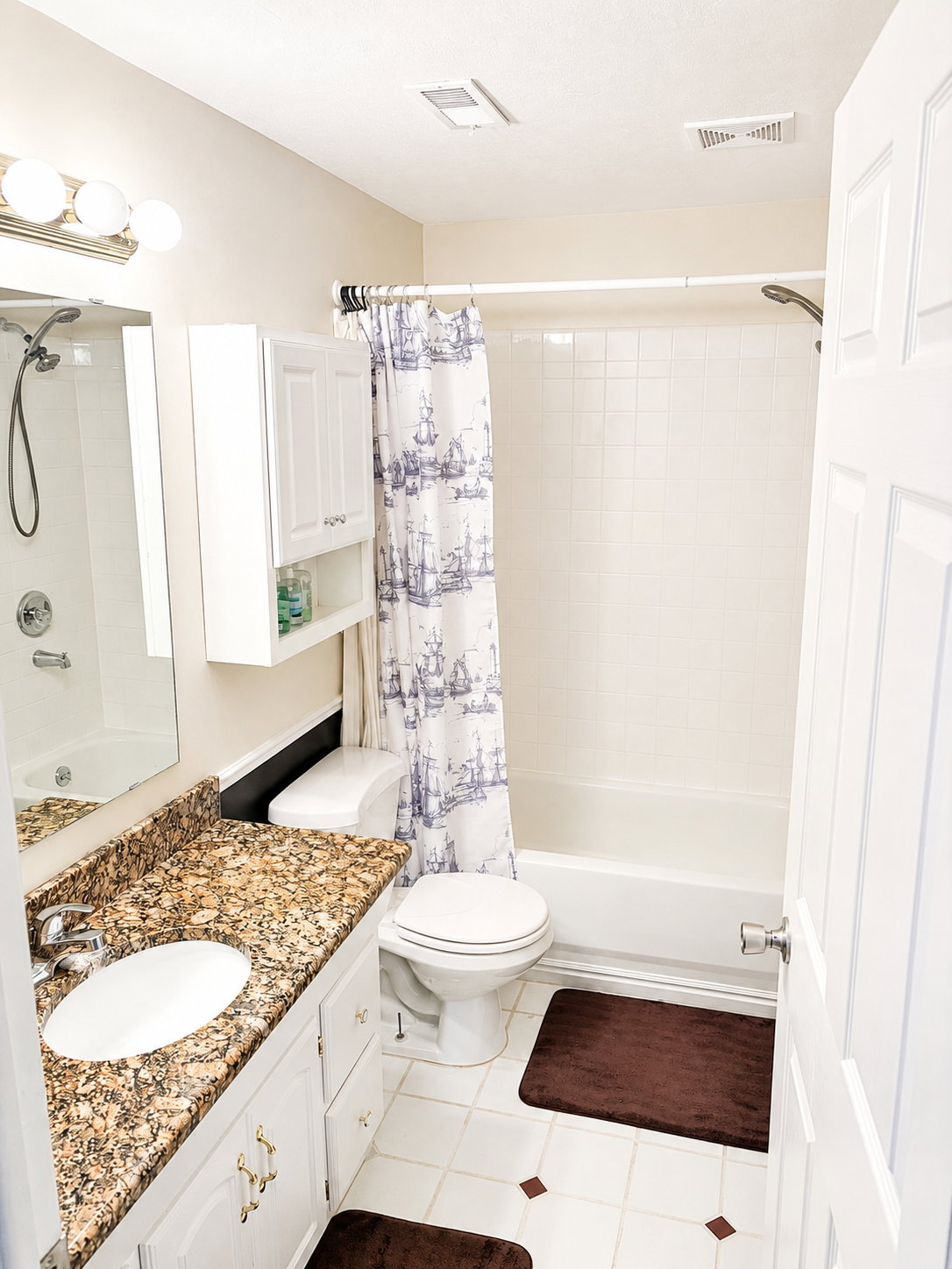 Bathroom featuring a white vanity with a granite-style countertop, undermount sink, and chrome faucet