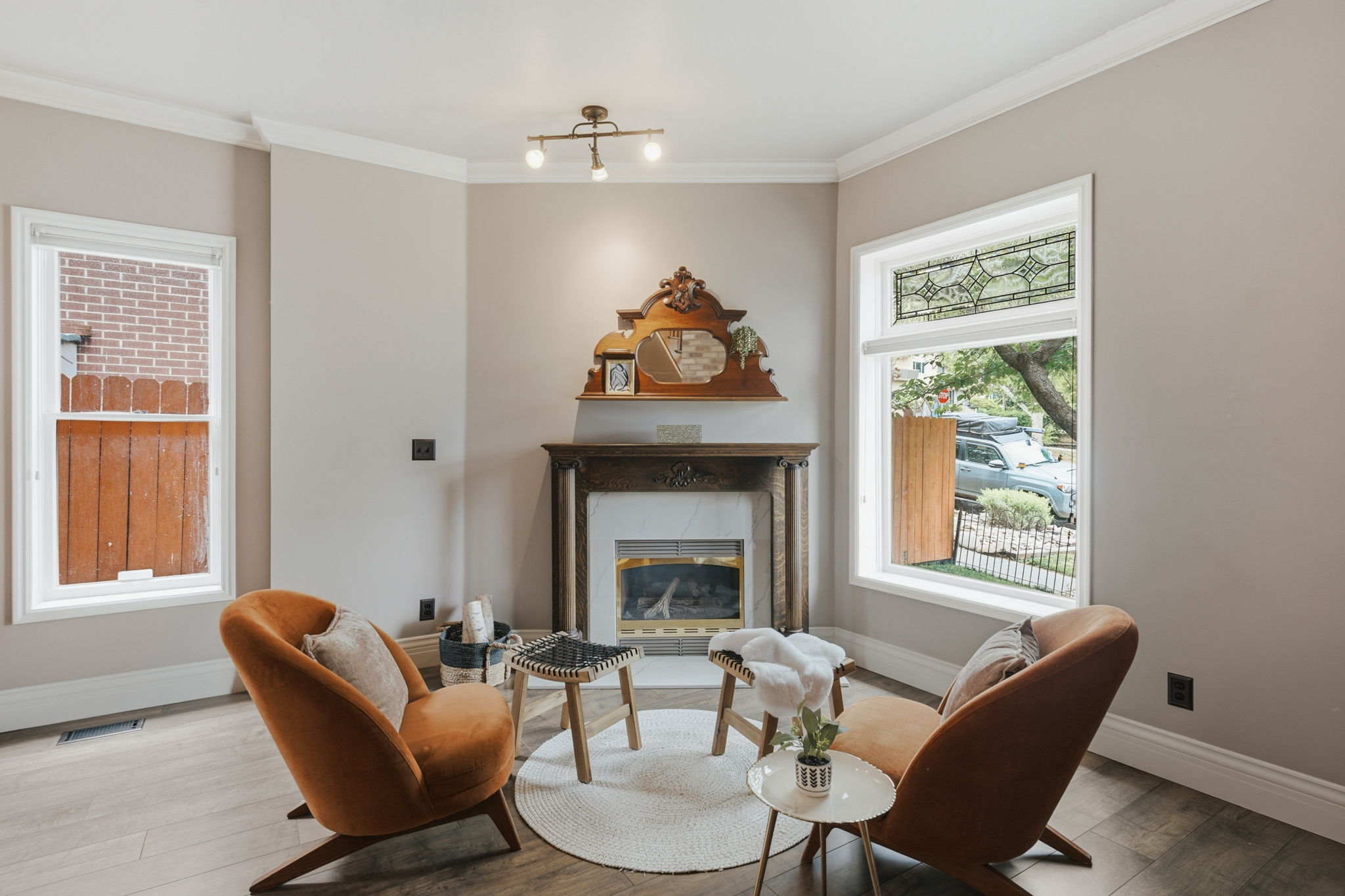 Living area featuring wood-finish flooring, a decorative fireplace with a mantel, and crown molding