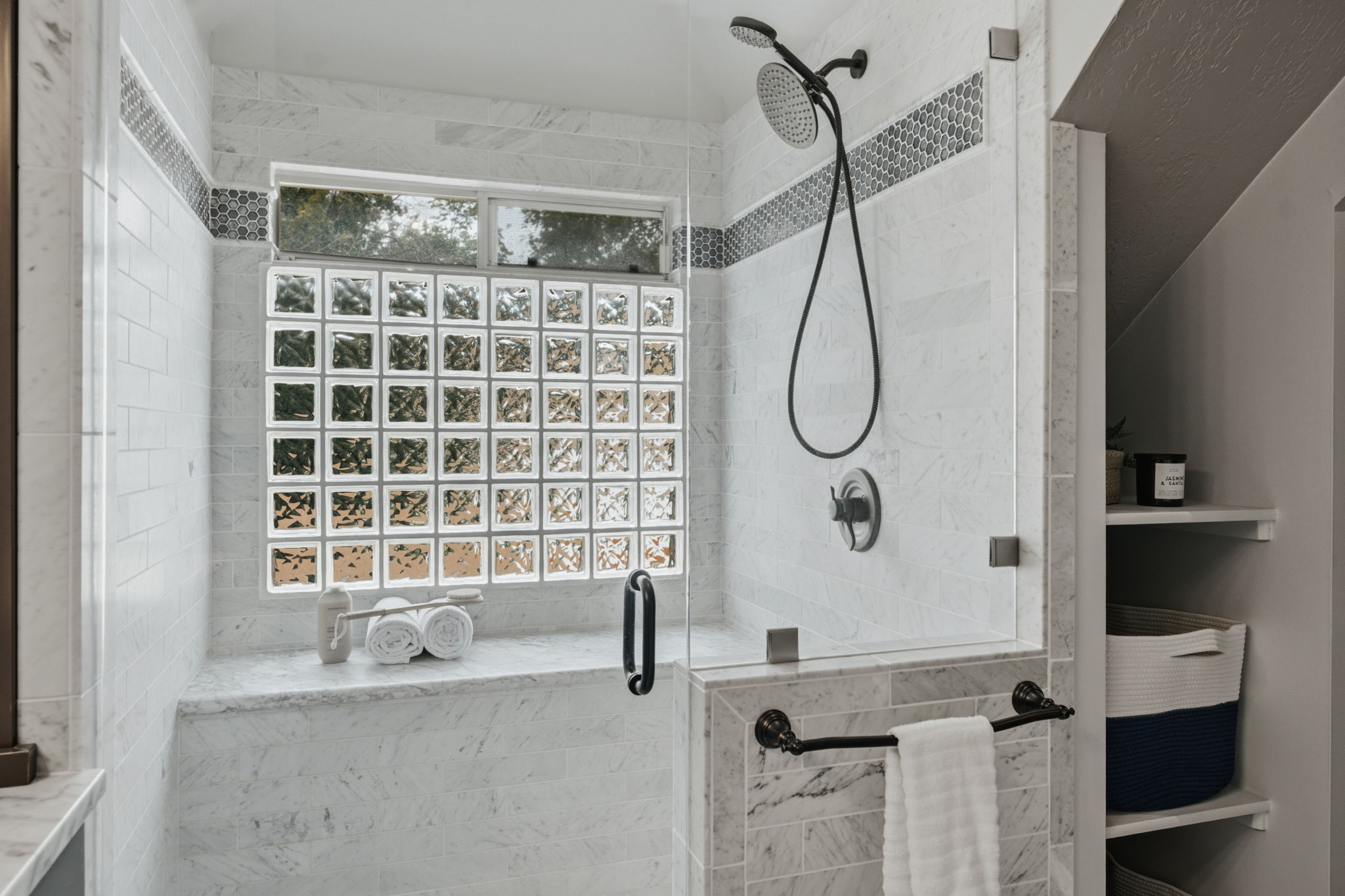 Enclosed shower featuring a clear glass door, a glass block window, and dual shower heads