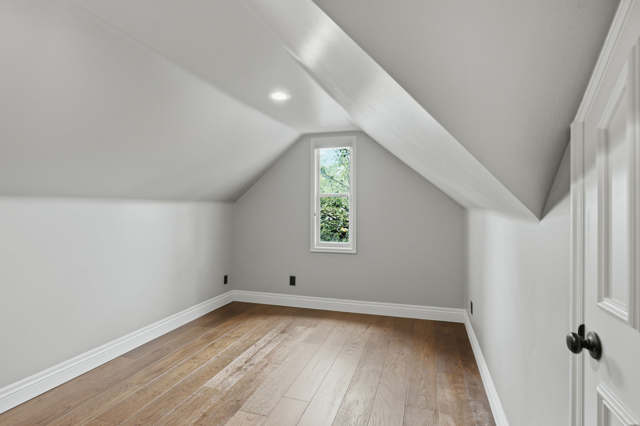 Attic space featuring wood-finish flooring and a single window
