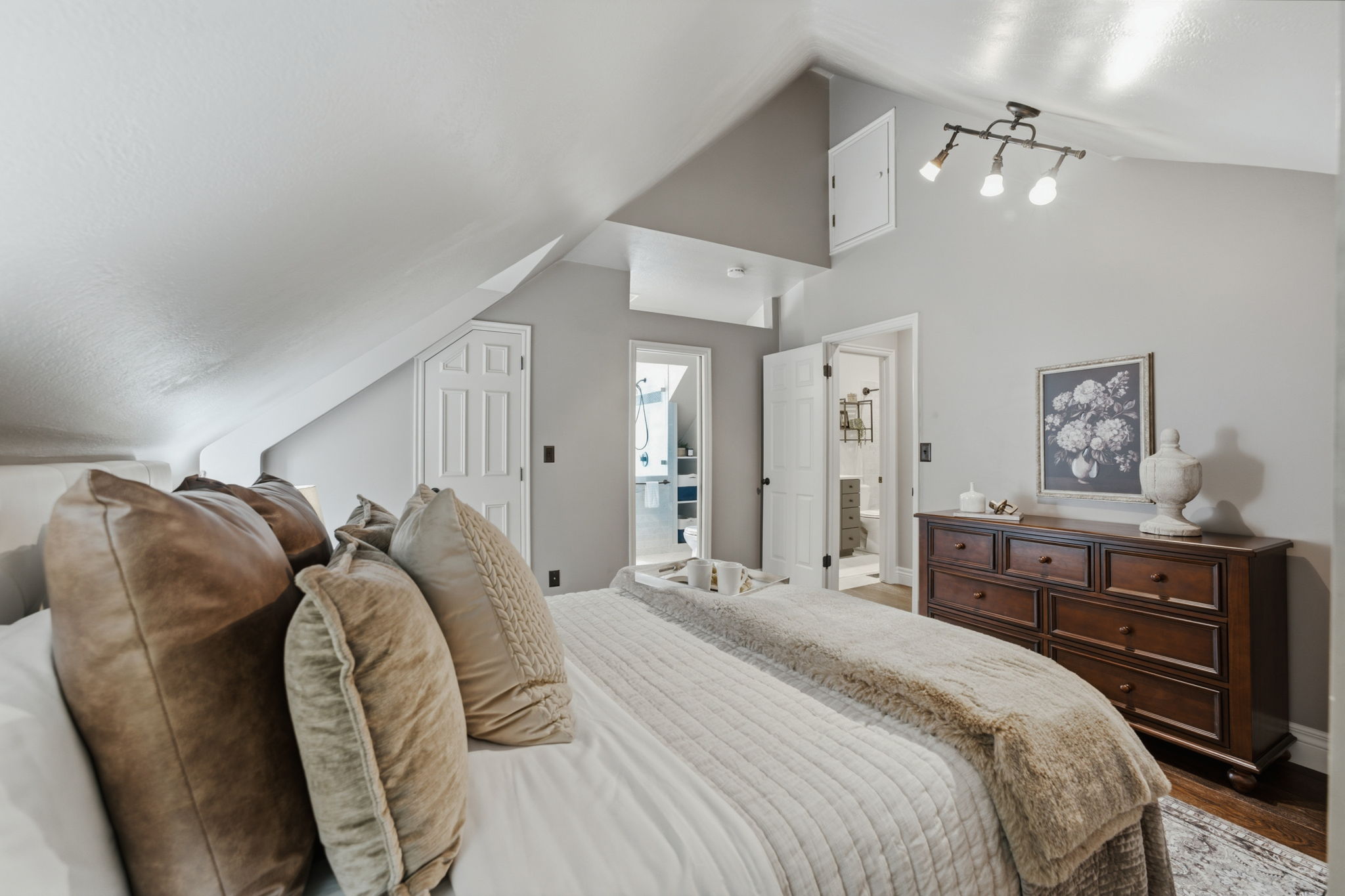 Bedroom featuring sloped ceilings, track lighting, and a white paneled door