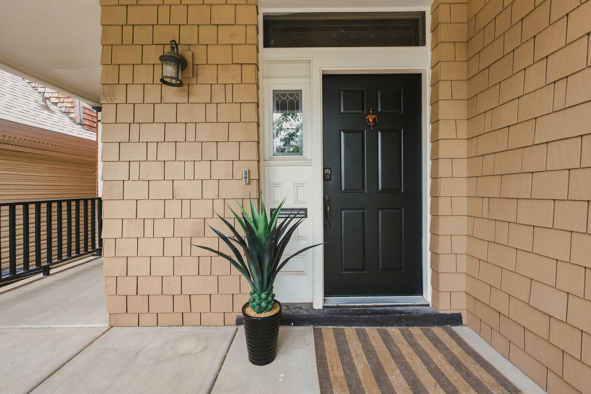 Entryway featuring a paneled black door with transom window, decorative sidelight, and an exterior sconce