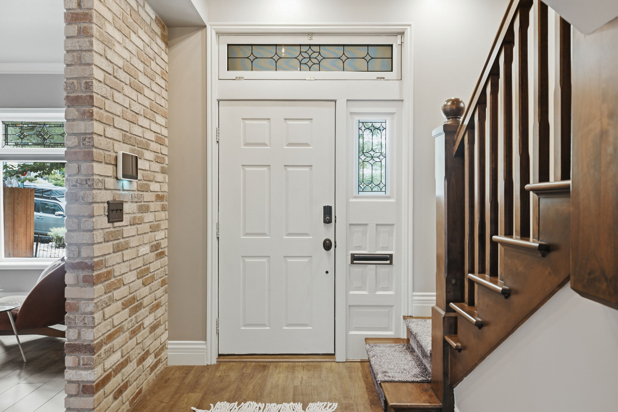 Entryway featuring a paneled door, leaded glass transom and sidelight, and wood-finish flooring