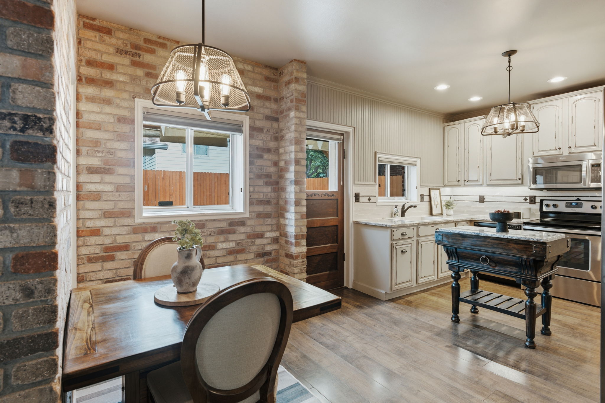 Dining area featuring exposed brick walls, a wood-finish dining table, and a contemporary chandelier