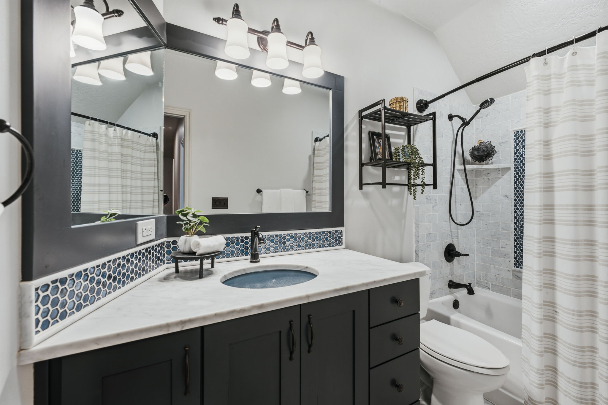 Bathroom featuring a single vanity with a white countertop, dark wood-finish cabinetry, and a blue hexagonal tile backsplash