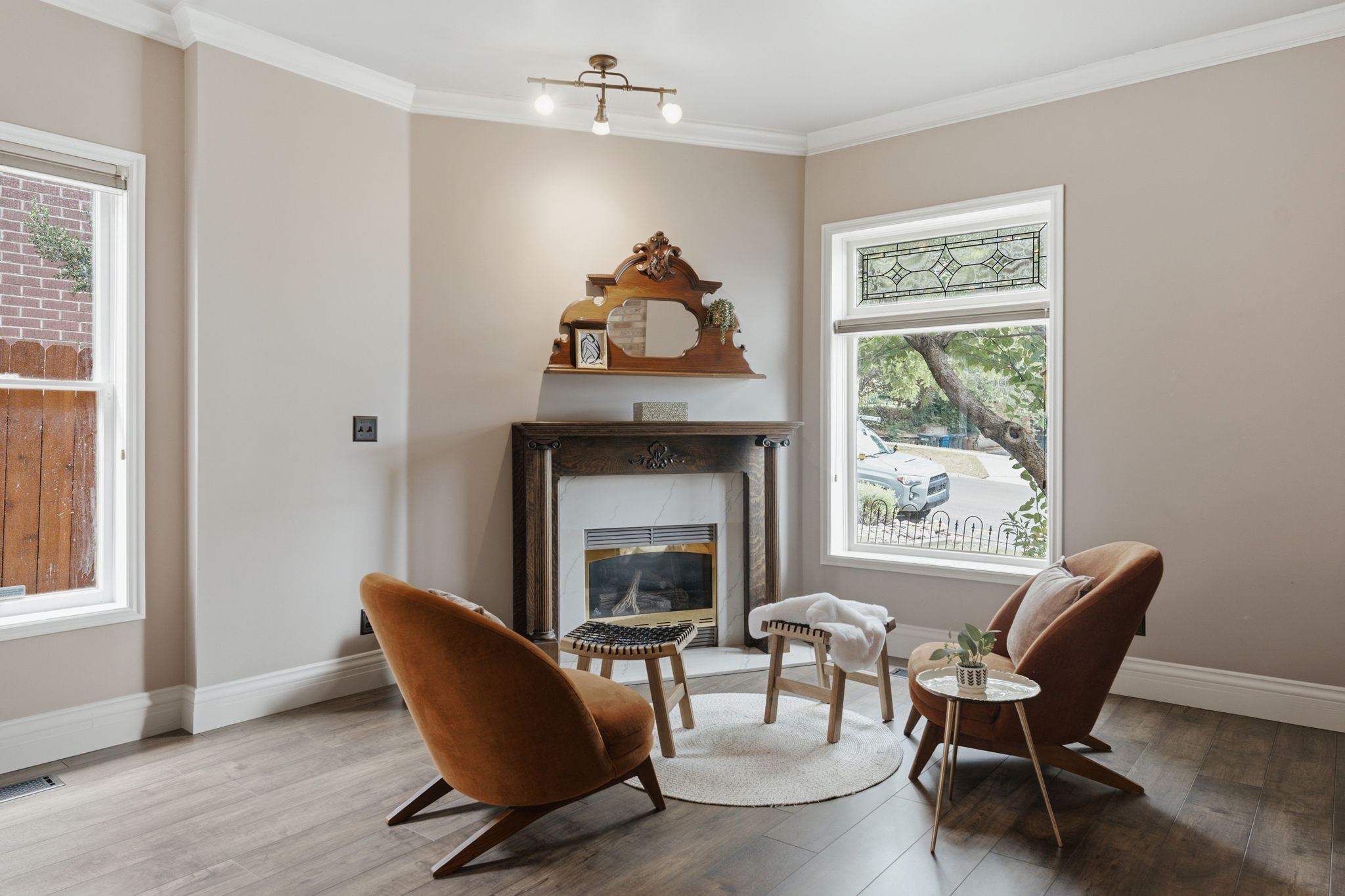 Inviting living area featuring a decorative fireplace with a carved wood mantel, wood-finish flooring, and crown molding