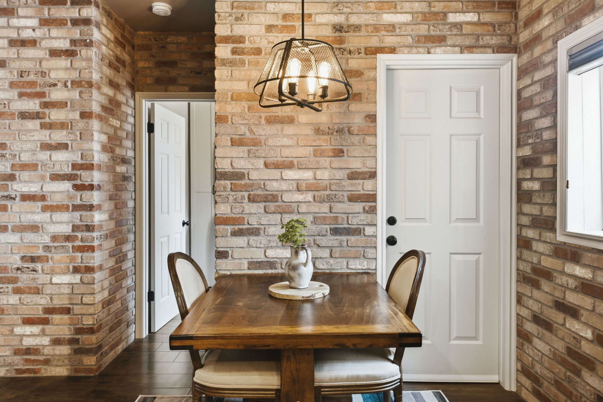 Exposed brick walls, dark wood-finish flooring, and a contemporary caged pendant light fixture