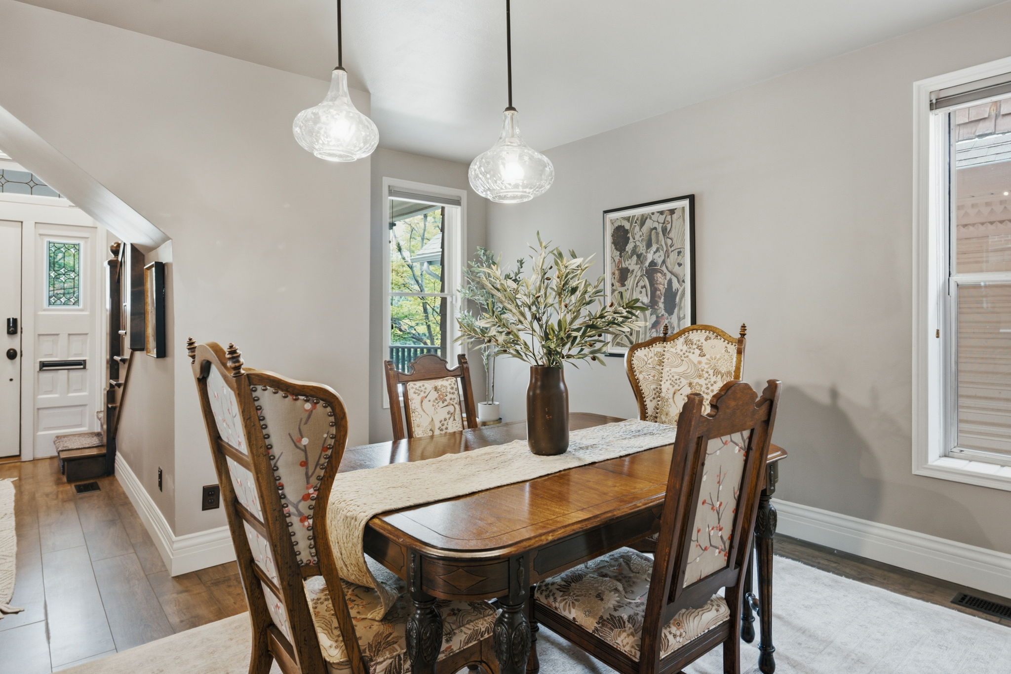 Dining area featuring wood-finish flooring, two pendant light fixtures, and a window with exterior views