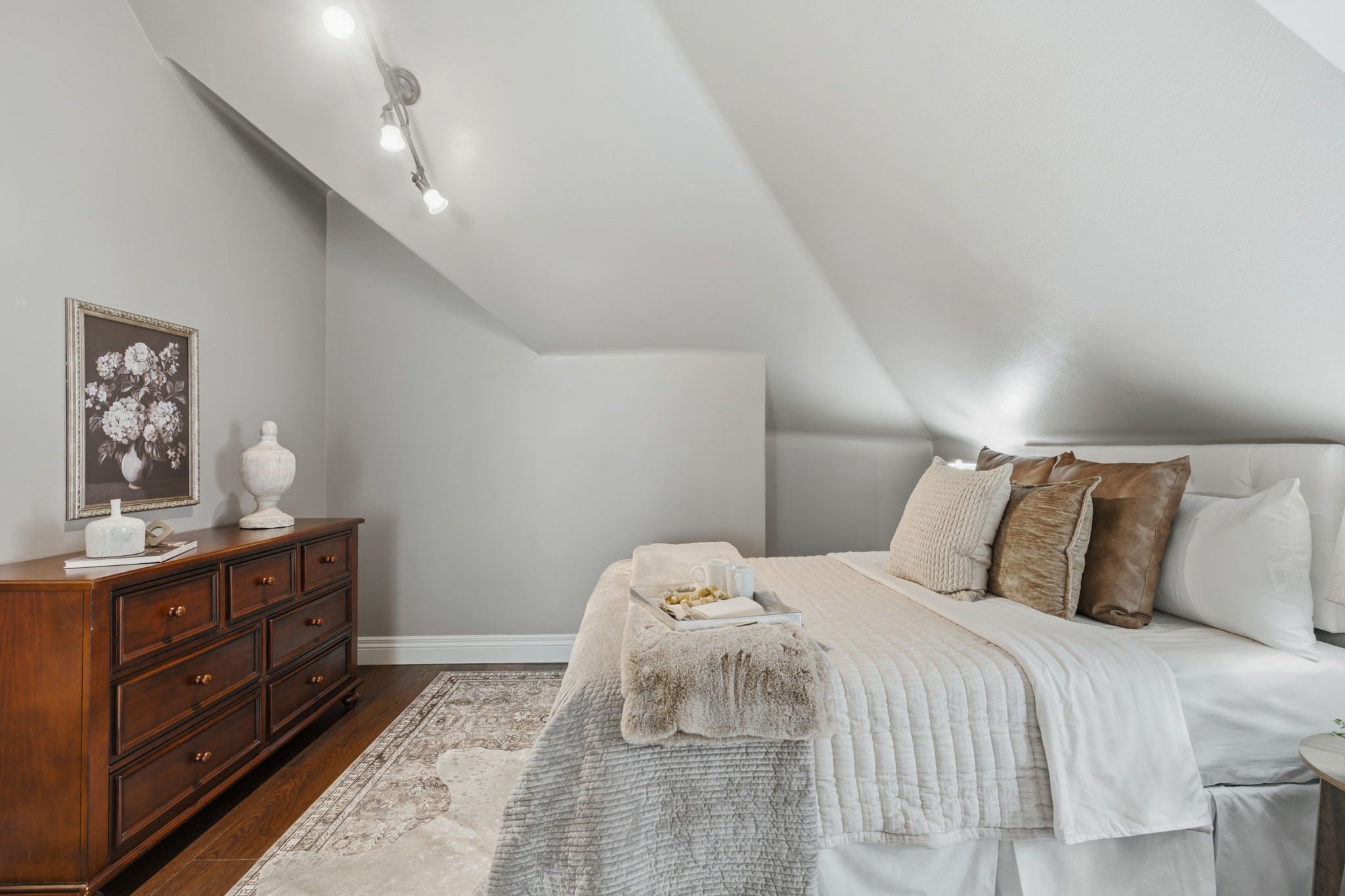Attic room featuring sloped ceilings, track lighting, and wood-finish flooring