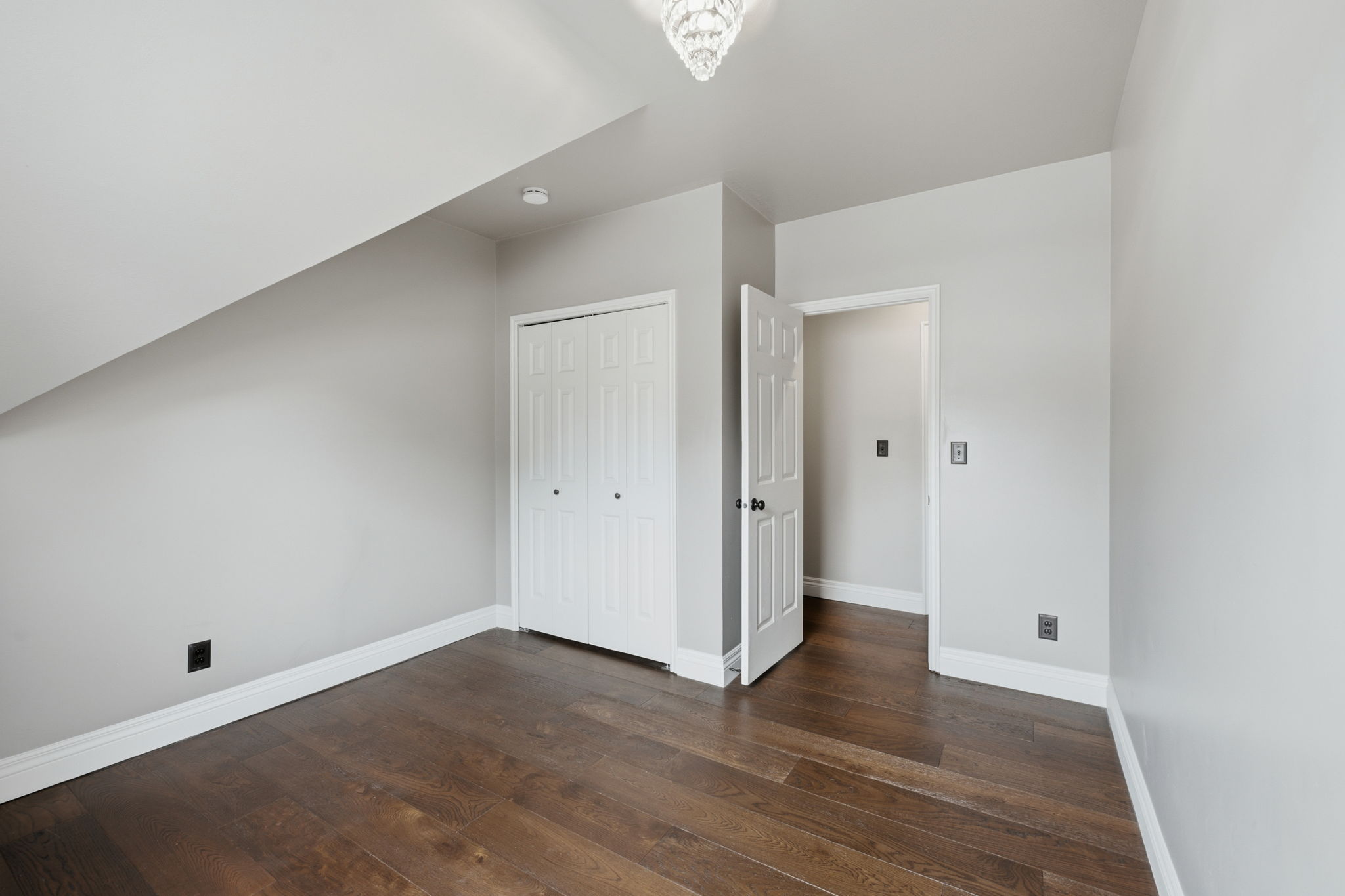 Spacious room featuring wood-finish flooring, light grey walls, and white trim