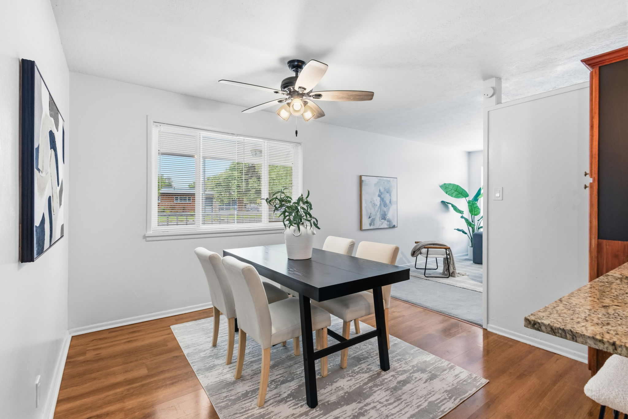 Dining area featuring wood-finish flooring, a multi-pane window with blinds, and a ceiling fan with integrated lighting