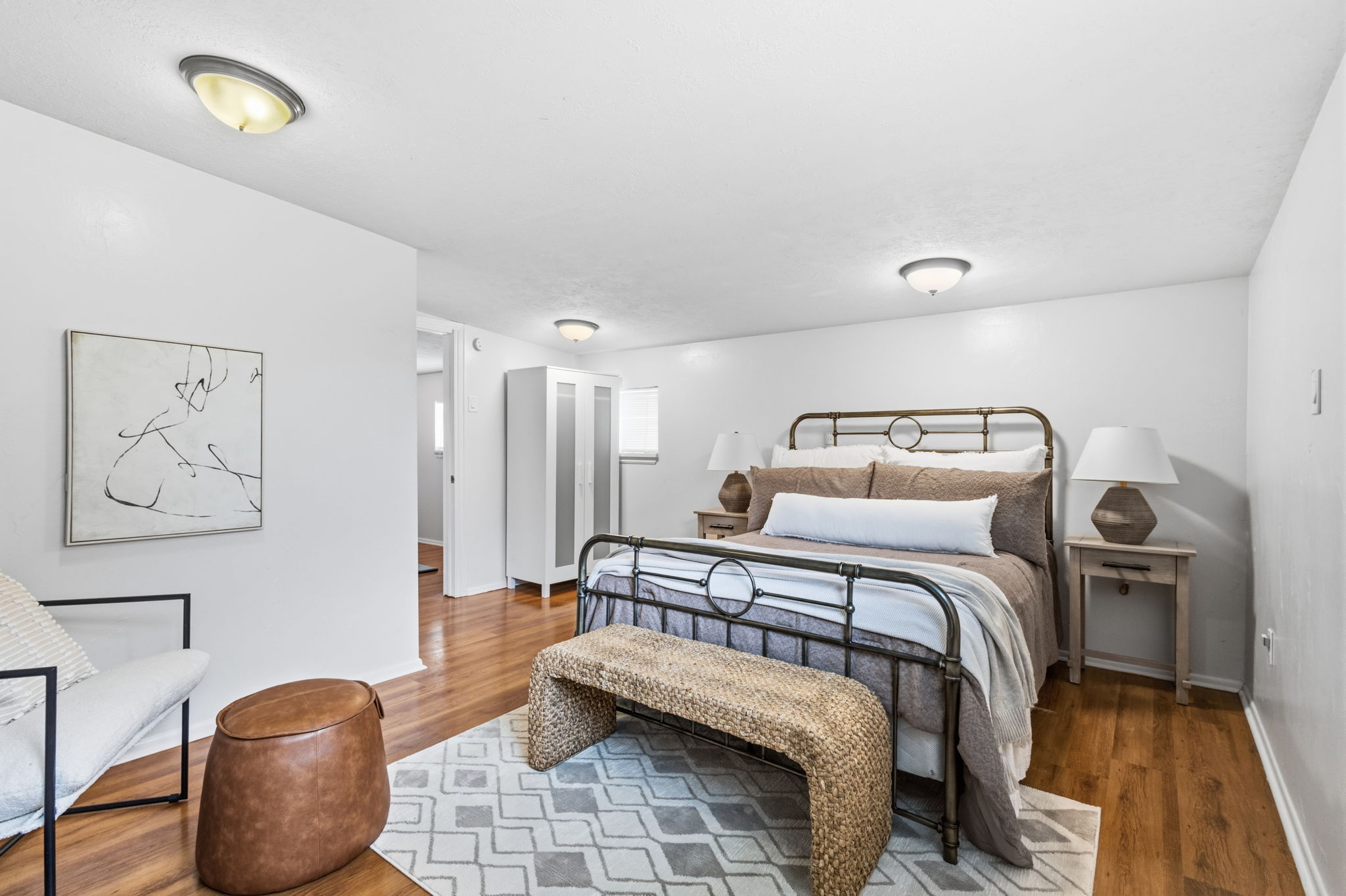 Spacious room featuring wood-finish flooring, light neutral wall paint, and multiple flush-mount ceiling lights