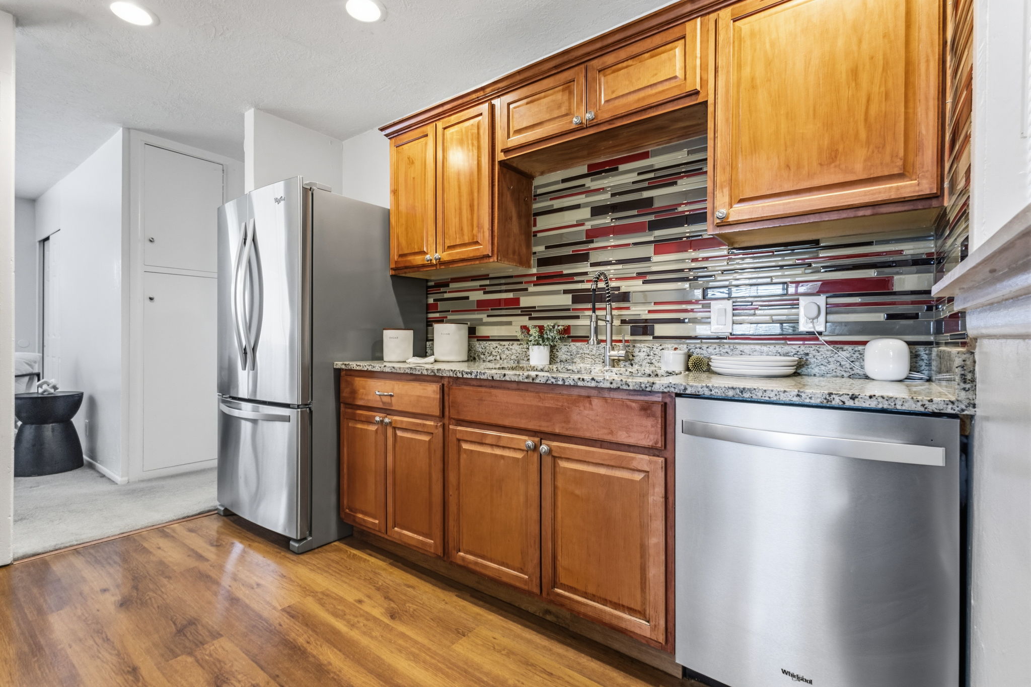 Kitchen featuring wood-finish flooring, granite countertops, and a modern tile backsplash