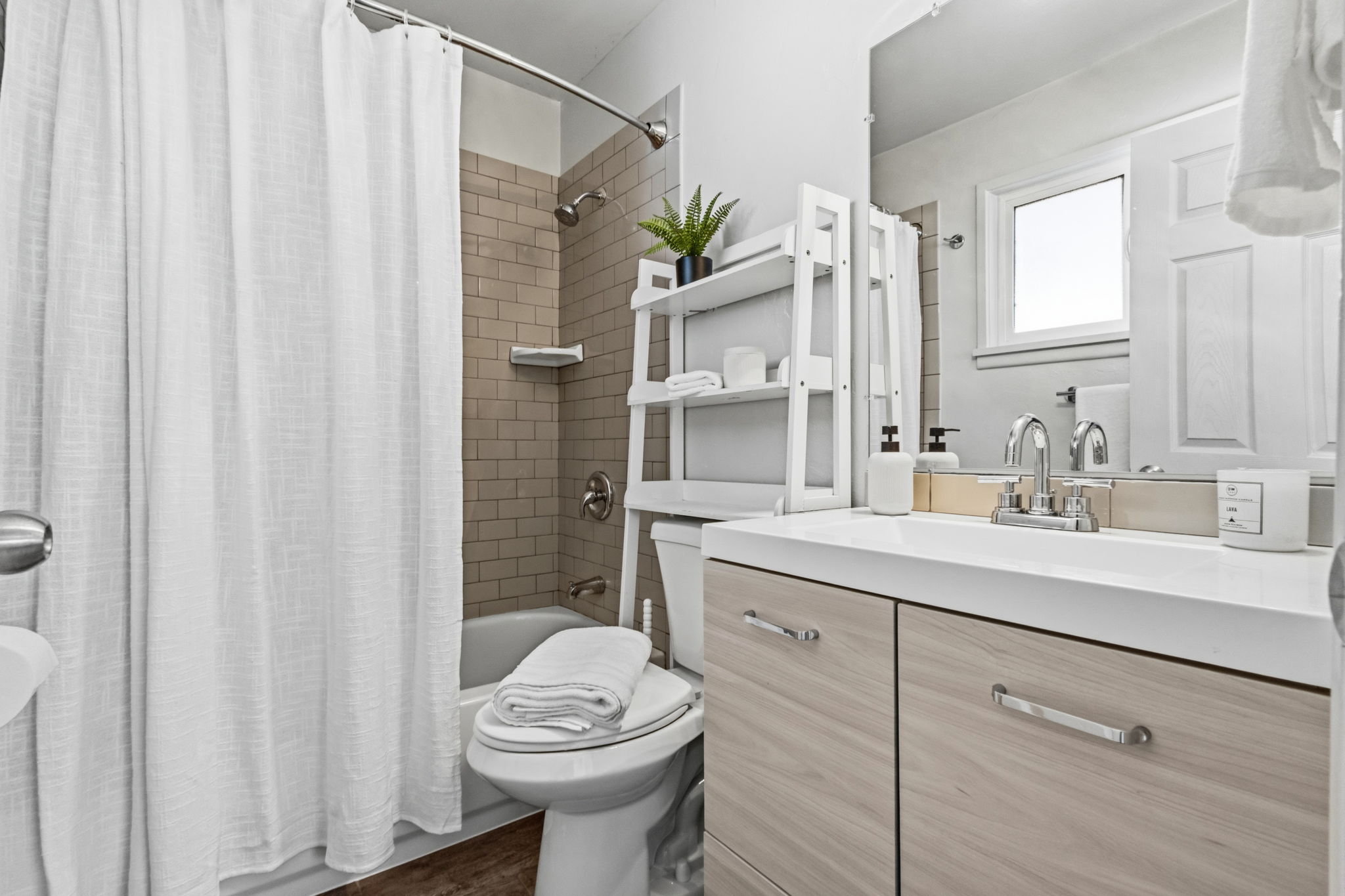 Bathroom featuring a light wood-finish vanity with chrome hardware, an integrated white sink, and a framed mirror