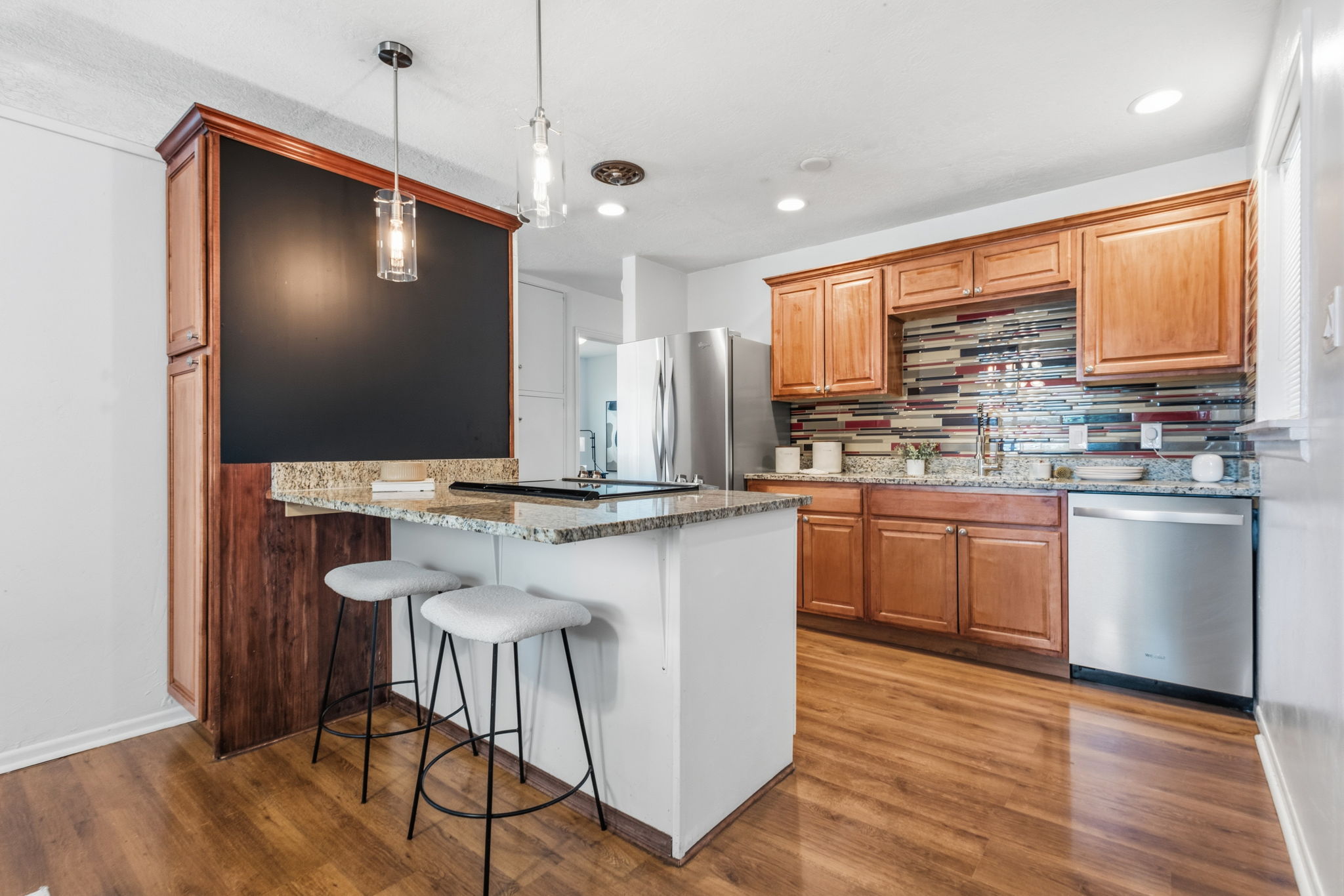 Kitchen featuring wood-finish flooring, a multi-tone tile backsplash, and light wood cabinetry