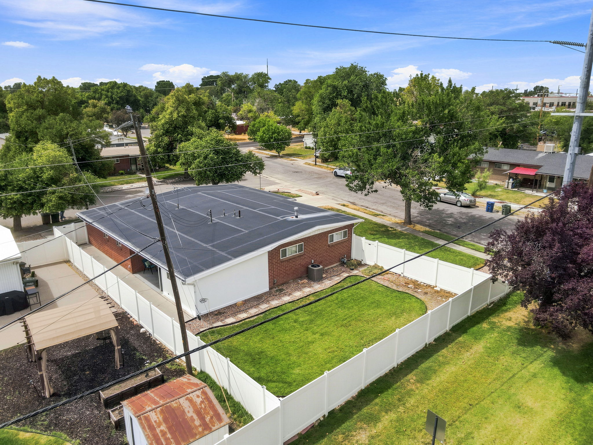 Fenced backyard with a manicured lawn, brick exterior, and a flat roof