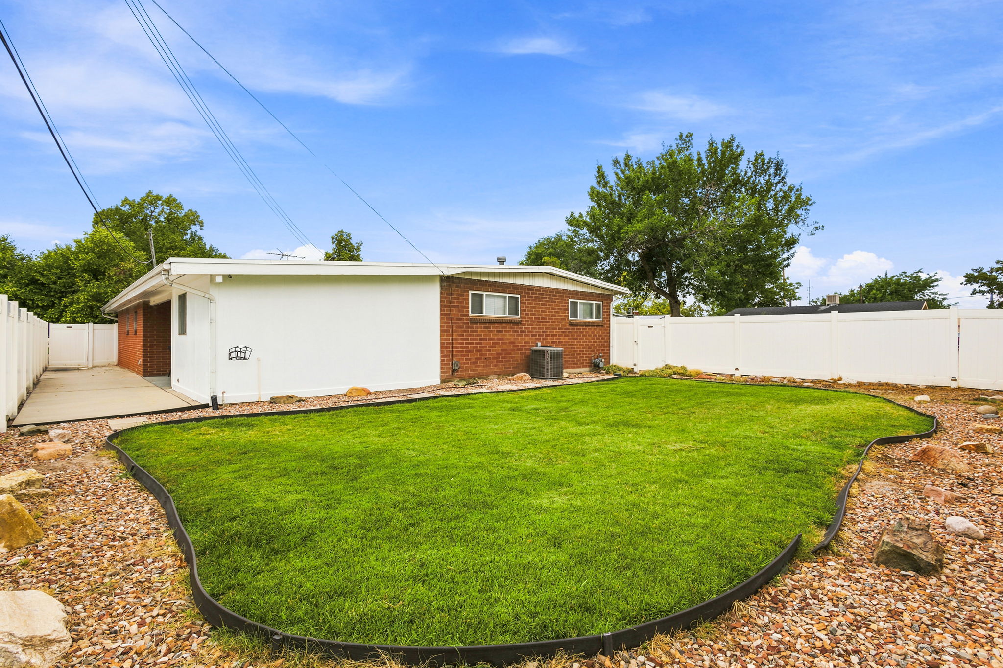 Expansive backyard featuring a manicured lawn area, gravel landscaping, and a privacy fence