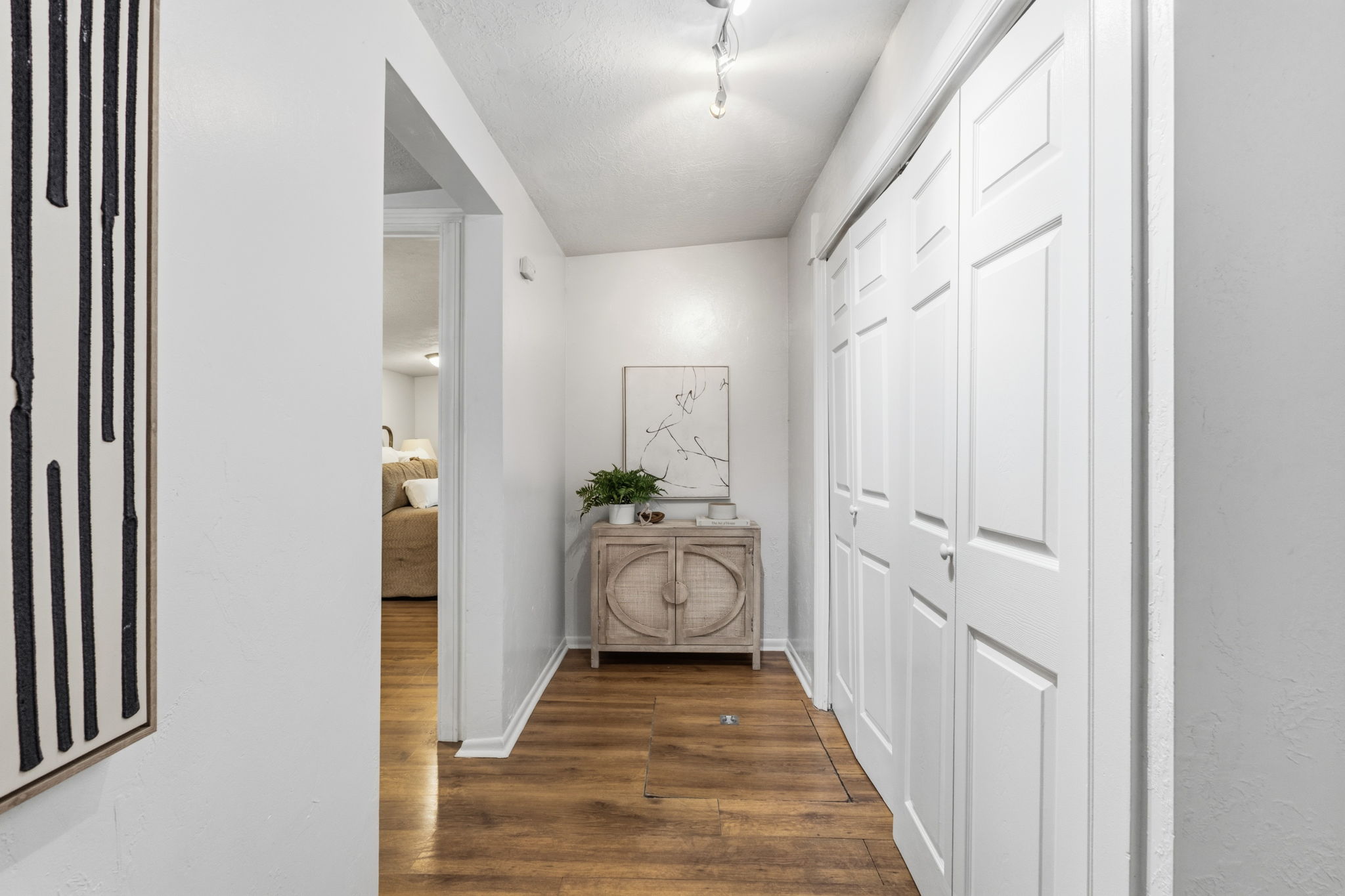Hallway featuring wood-finish flooring, white walls, and bright overhead lighting