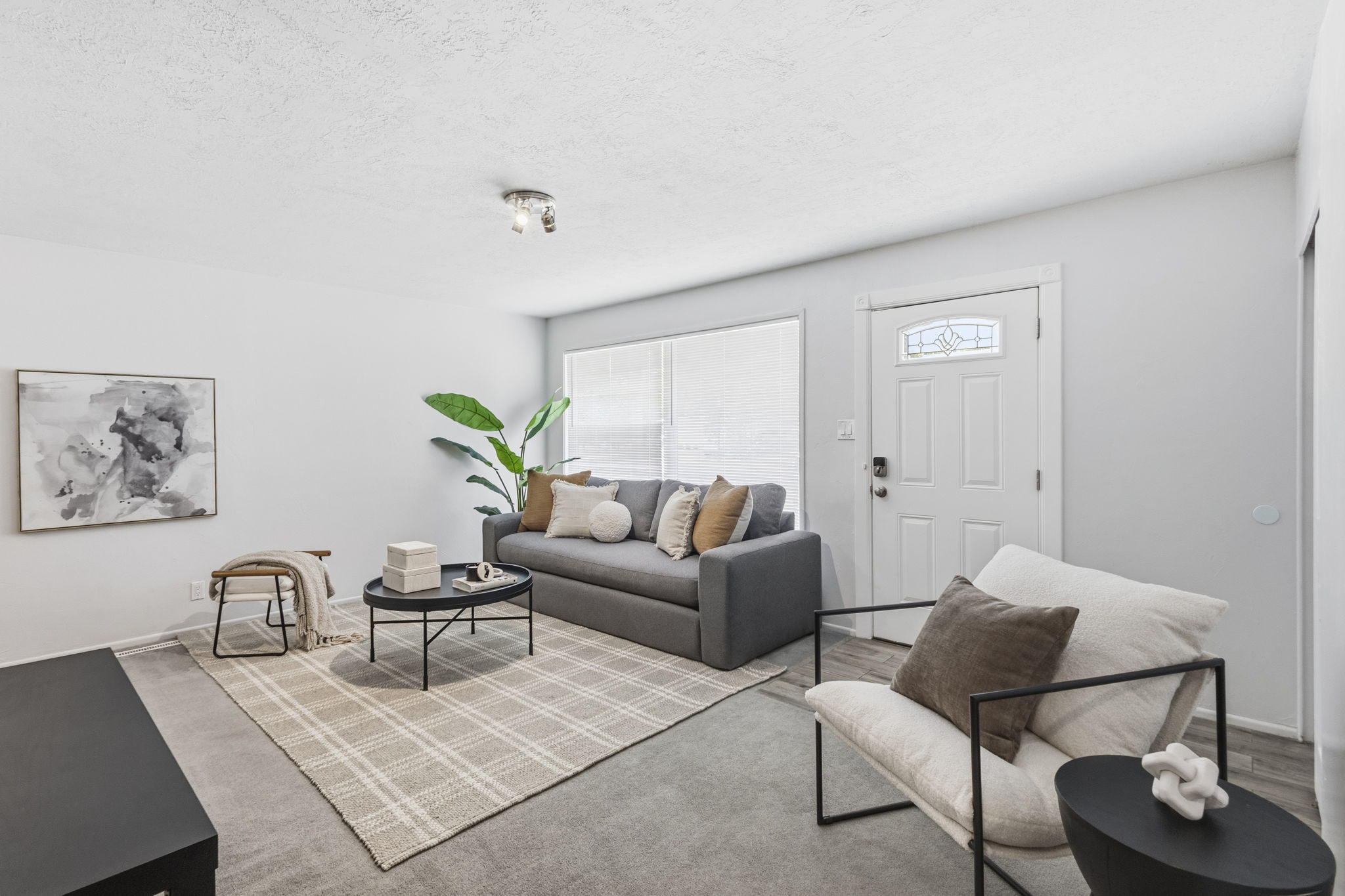 Spacious living area featuring light-toned walls, recessed lighting, and a front entry door with decorative glass