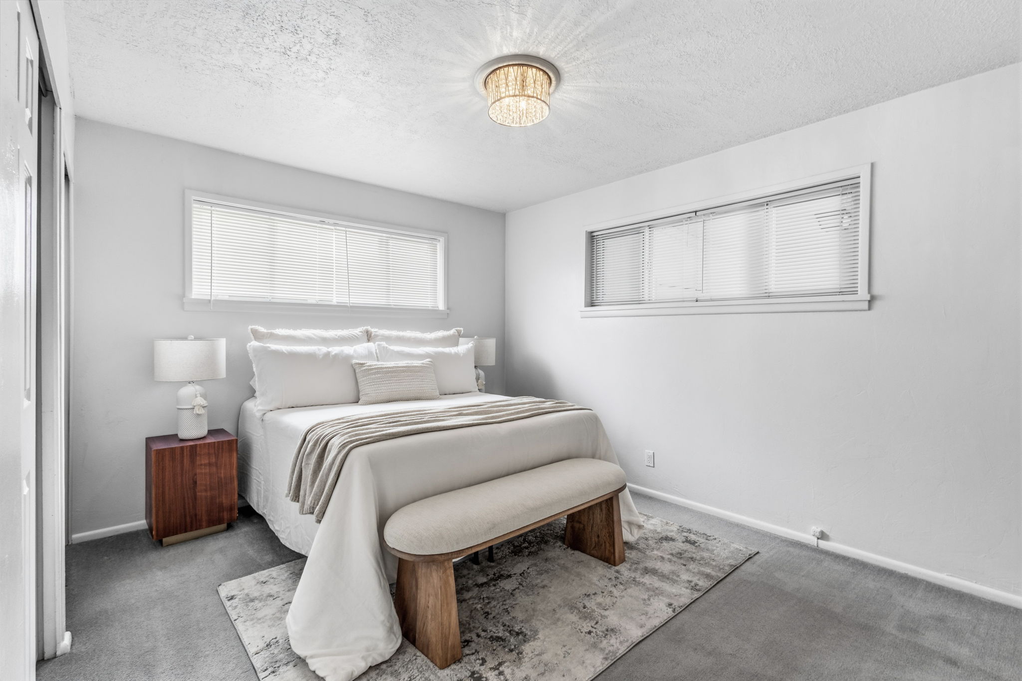 Bright room with soft gray carpeting, a built-in closet, and a contemporary chandelier