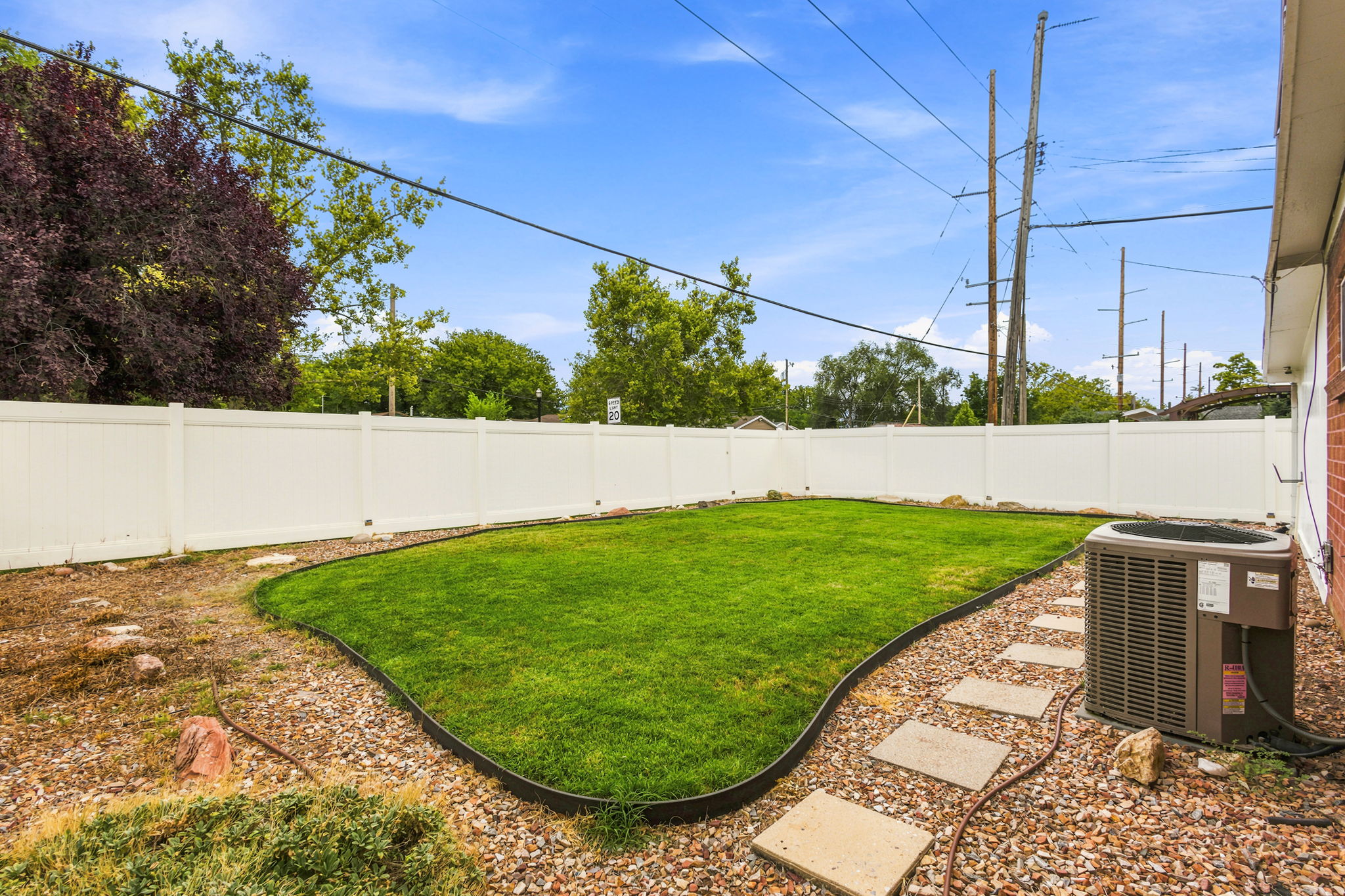 Private backyard featuring a well-maintained lawn, white privacy fencing, and stone stepping stones