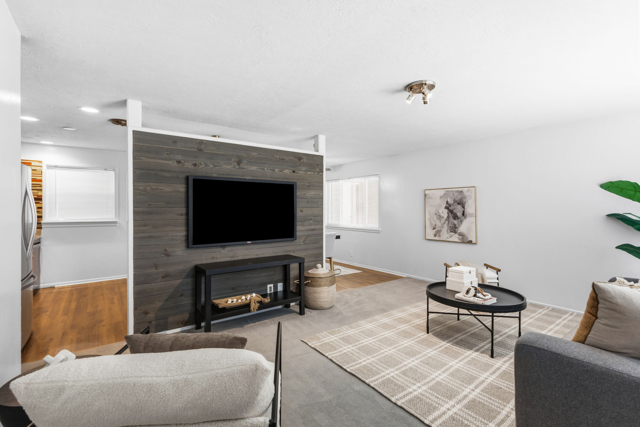 Living area featuring a prominent dark wood-paneled accent wall, light gray walls, and recessed lighting