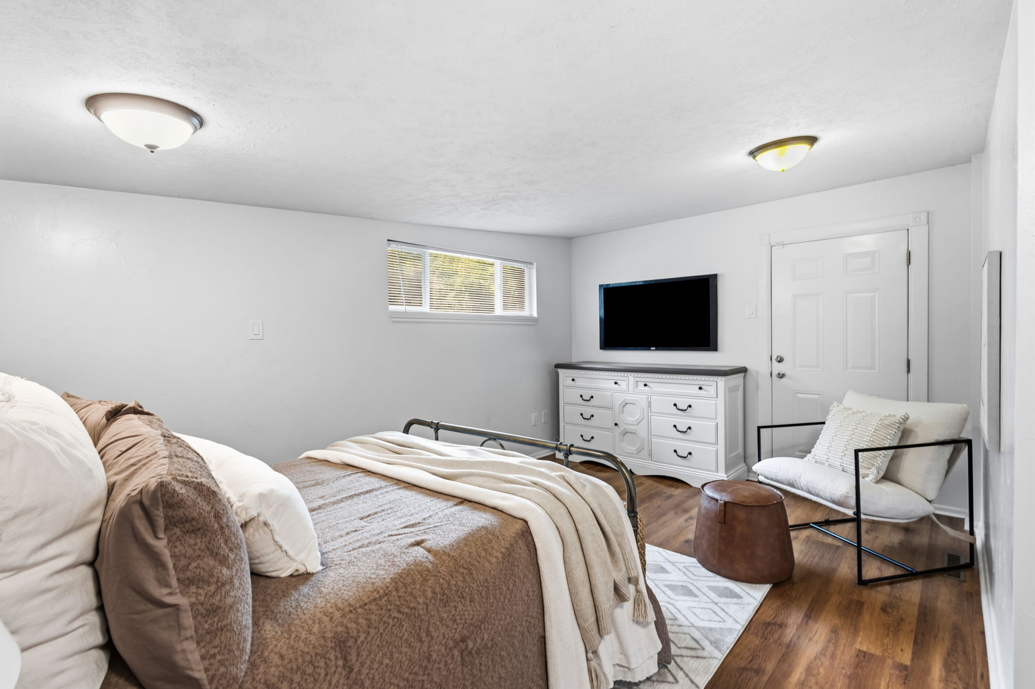 Bright room featuring wood-finish flooring, white walls, and a window providing natural light