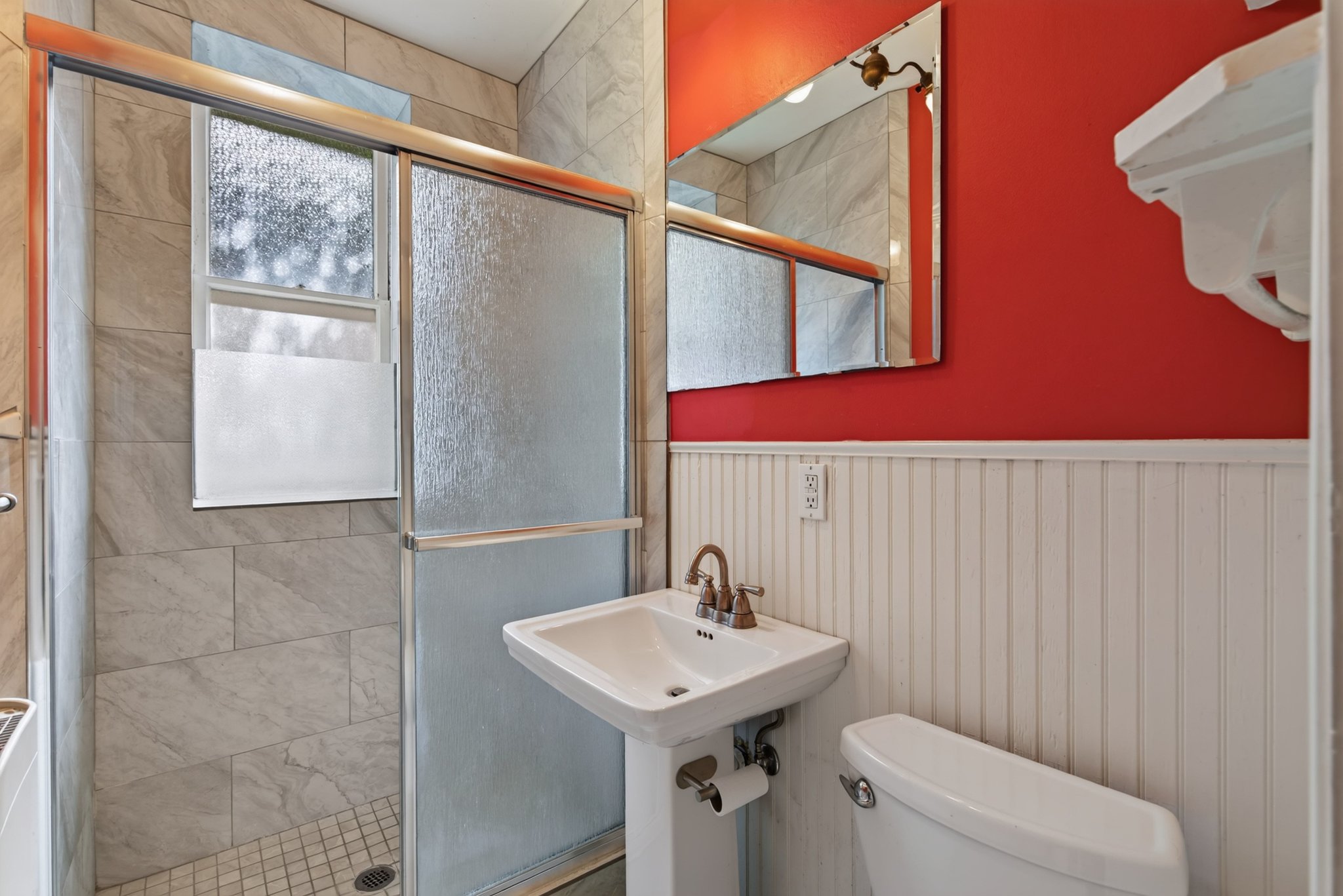 Bathroom featuring a shower with sliding frosted glass doors, a window, and tile surround