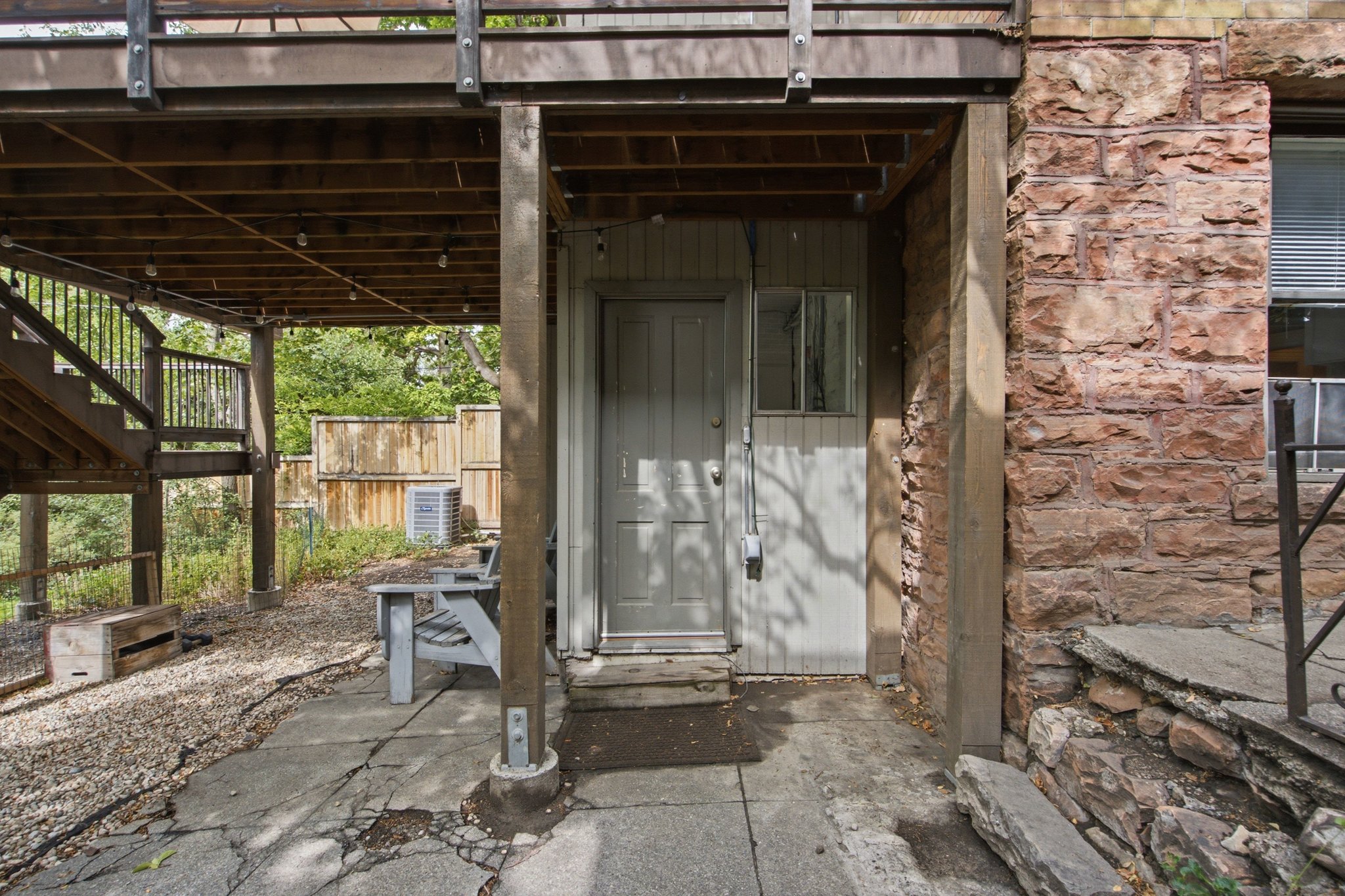 Stone façade exterior with a dedicated entrance, sheltered by an elevated wood deck
